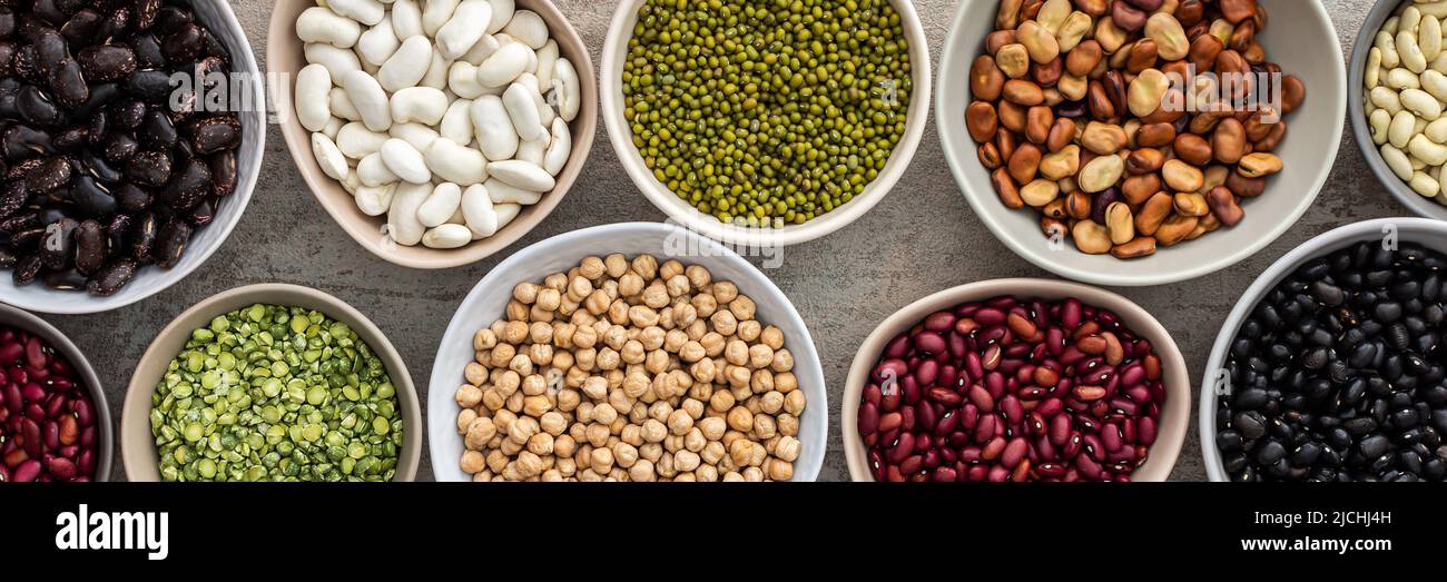 Banner of different types of legumes in bowls, yellow peas and chickpeas , colored beans and lentils, mung beans, top view, copy space Stock Photo