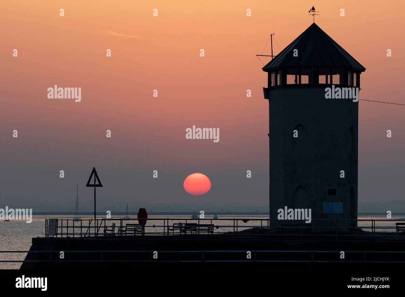 The setting sun at Brightlingsea in Essex UK.  Bateman's Tower in the foreground. Stock Photo