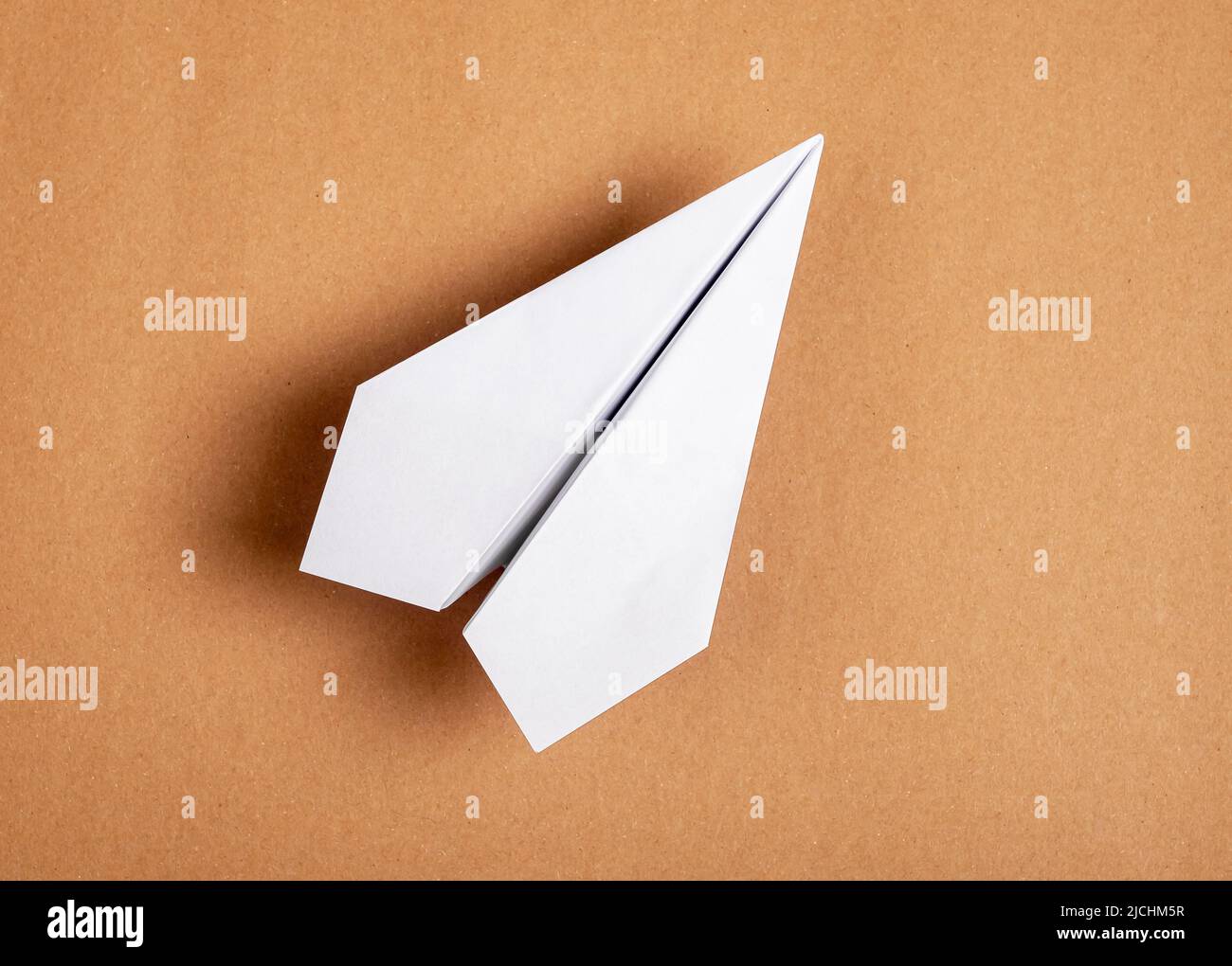 White origami plane on brown background. Paper folding art. Architecture model. High quality photo Stock Photo