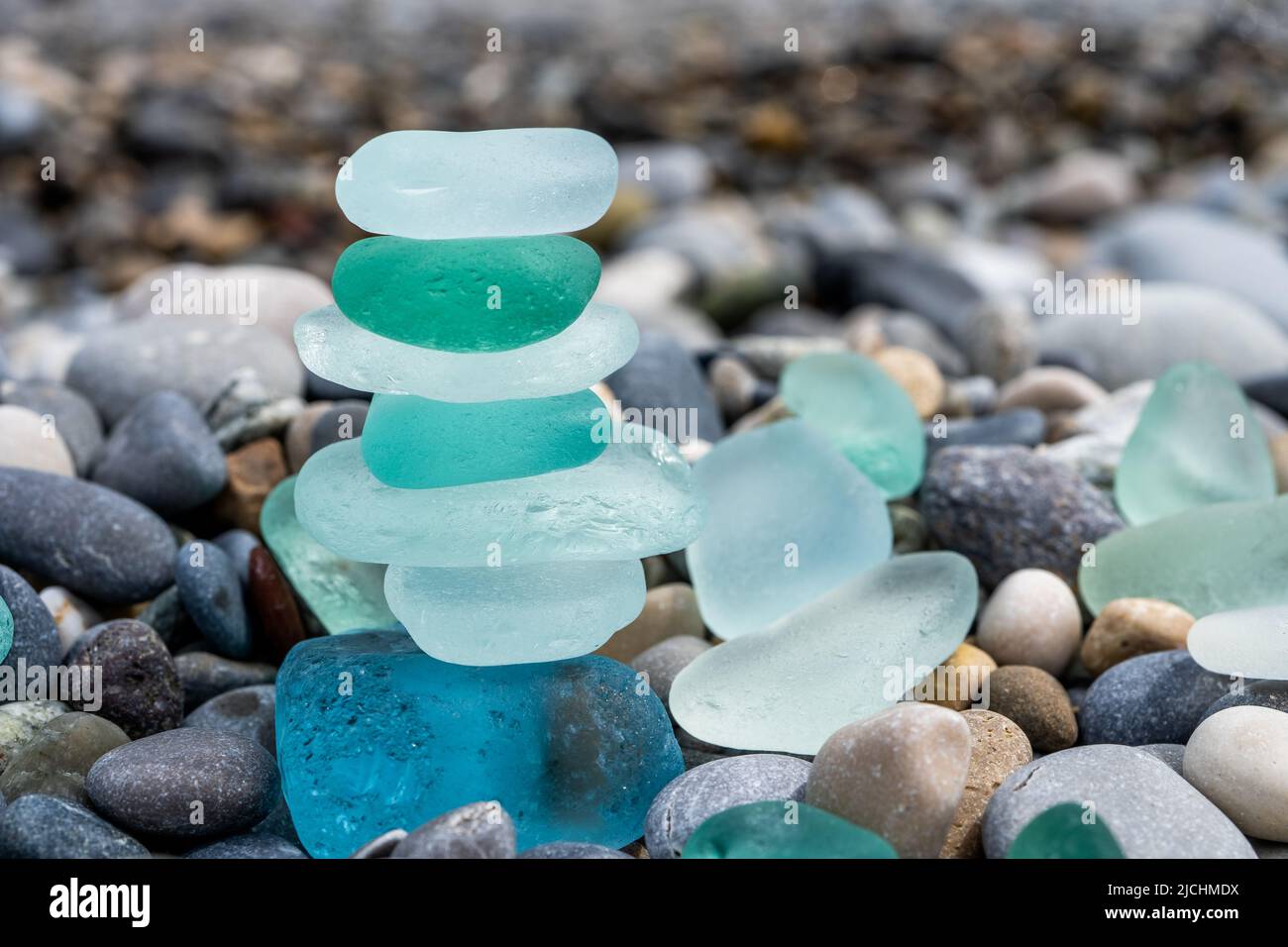 Colorful gemstones on a beach. Polish textured sea glass and stones on the  seashore. Green, blue shiny glass with multi-colored sea pebbles close-up.  Beach summer background. Stock Illustration