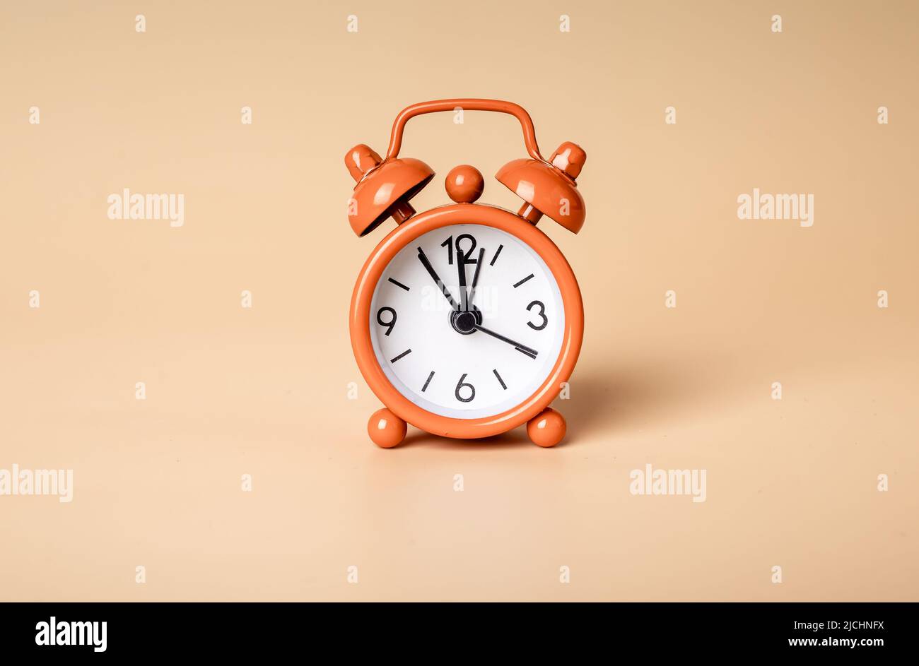 Retro styled bright orange alarm clock on background, photo Stock Photo