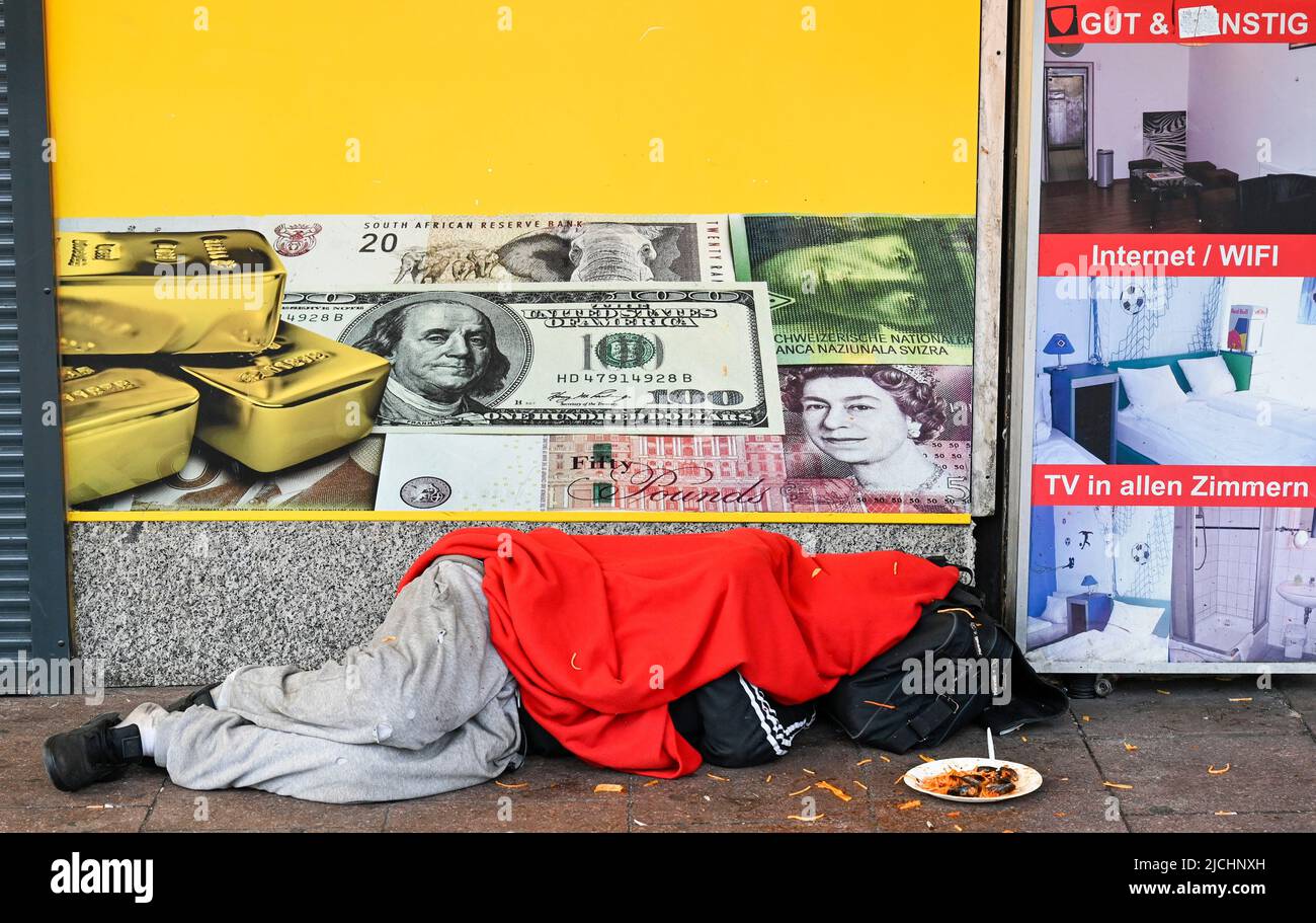 GERMANY, Hamburg, Reeperbahn, St. Pauli red light district, sleeping homeless person infront of closed money exchange shop, increasing poverty due to Corona pandemic and inflation crisis Stock Photo