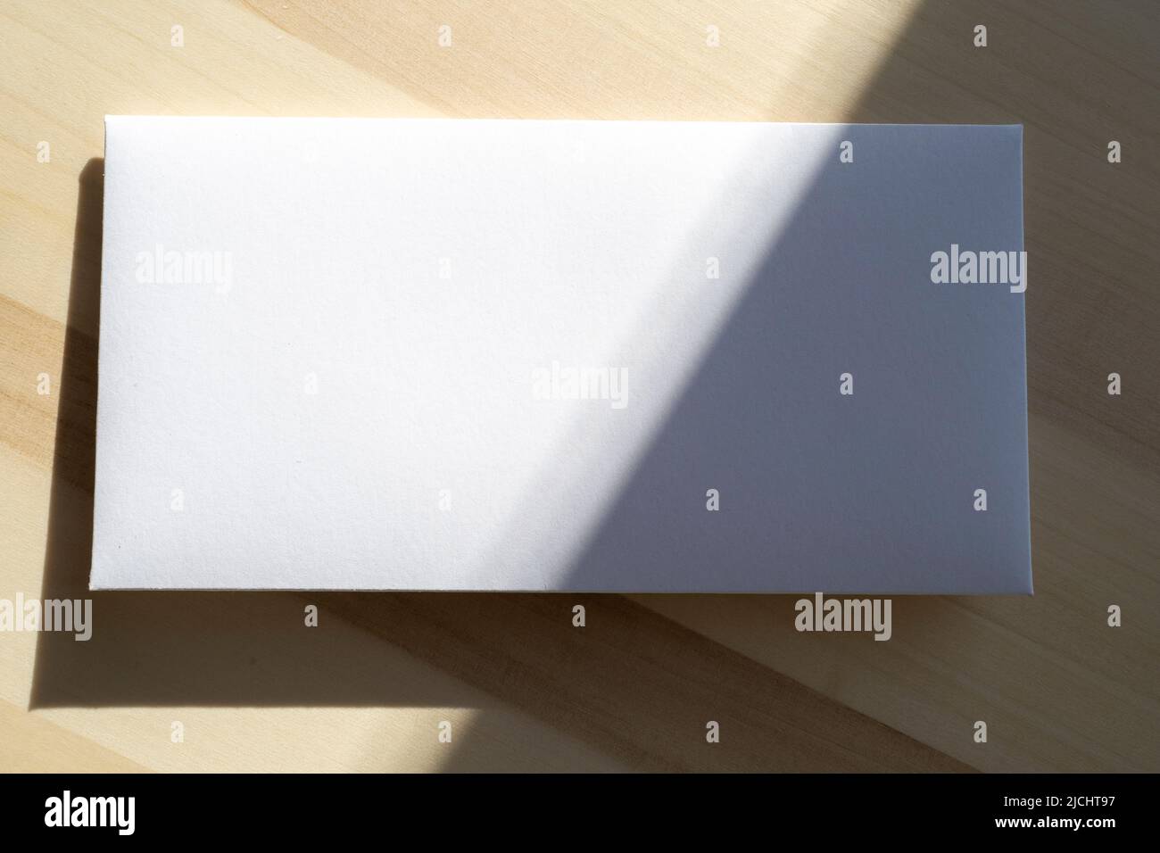 Blank white paper sheet, postcard, envelope as mockup and sunny light on surface Stock Photo