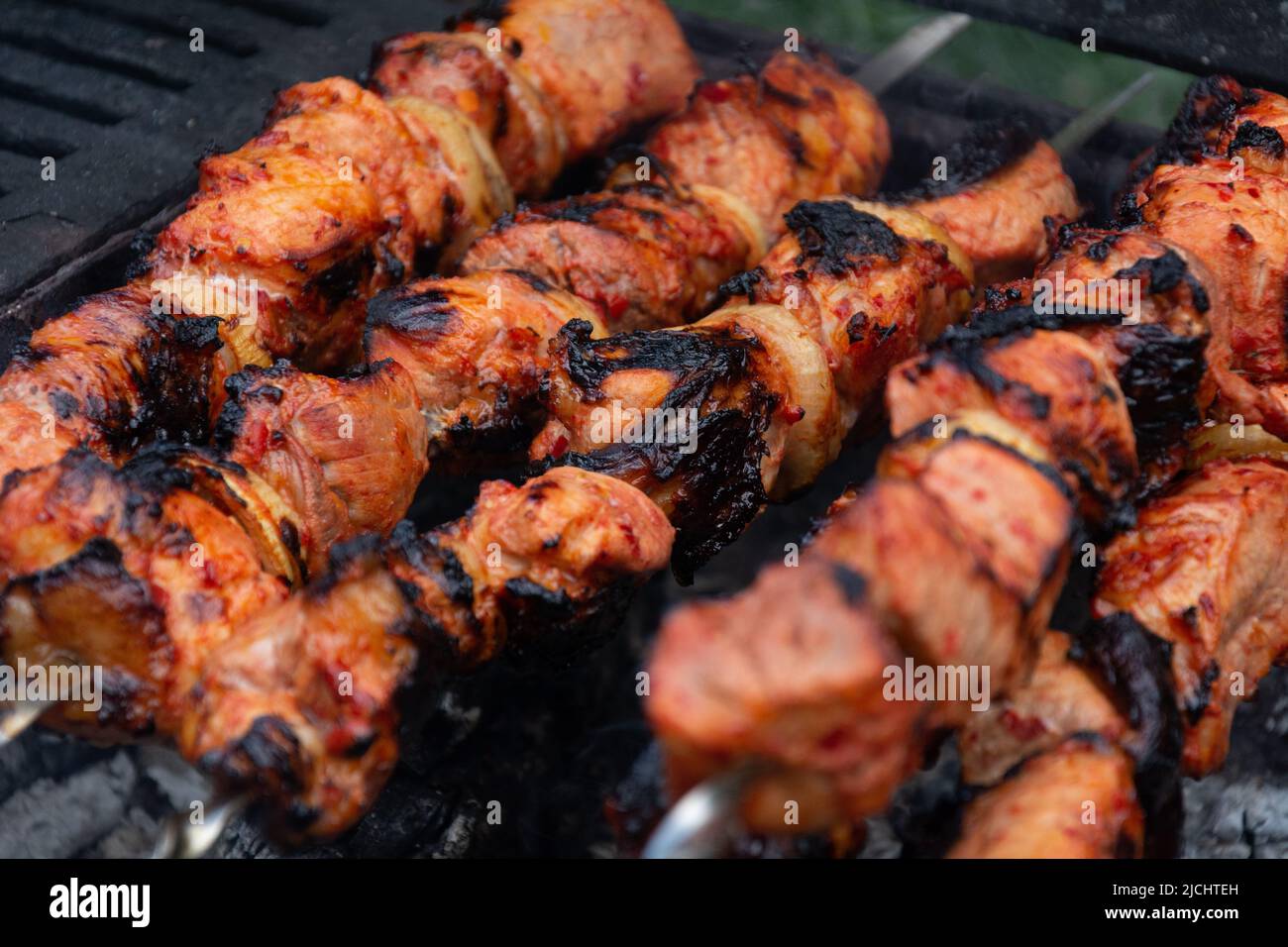 Kebab. Appetizing kebab marinated in red sauce with red pepper and onion is cooked on the grill Stock Photo