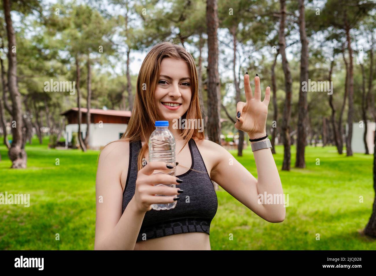 Happy woman wearing black sports bra standing on city park