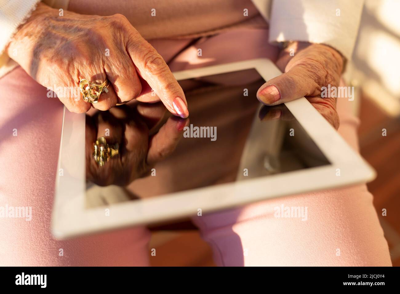 Close up of unrecognizable elderly person using a digital tablet. Concept of old people and new technologies. Stock Photo