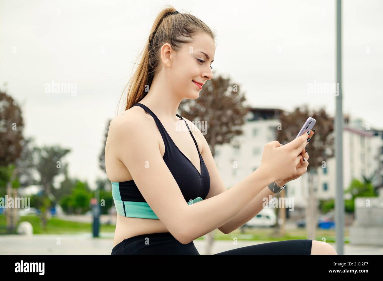 Happy sportive woman wearing sports bra standing on city park, outdoors