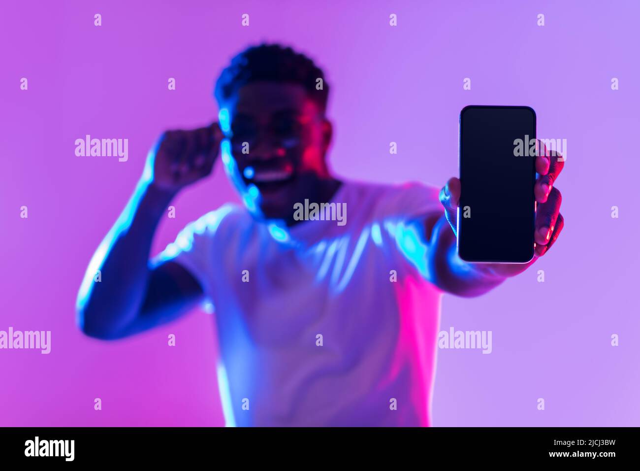 Cool mobile offer. Handsome African American guy demonstrating smartphone with blank screen in