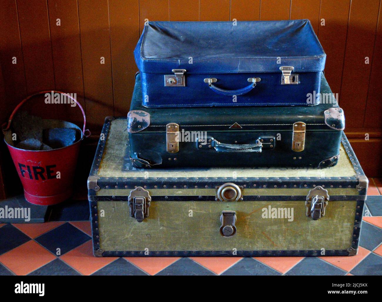 Stack of three vintage suitcases and a fire bucket Stock Photo