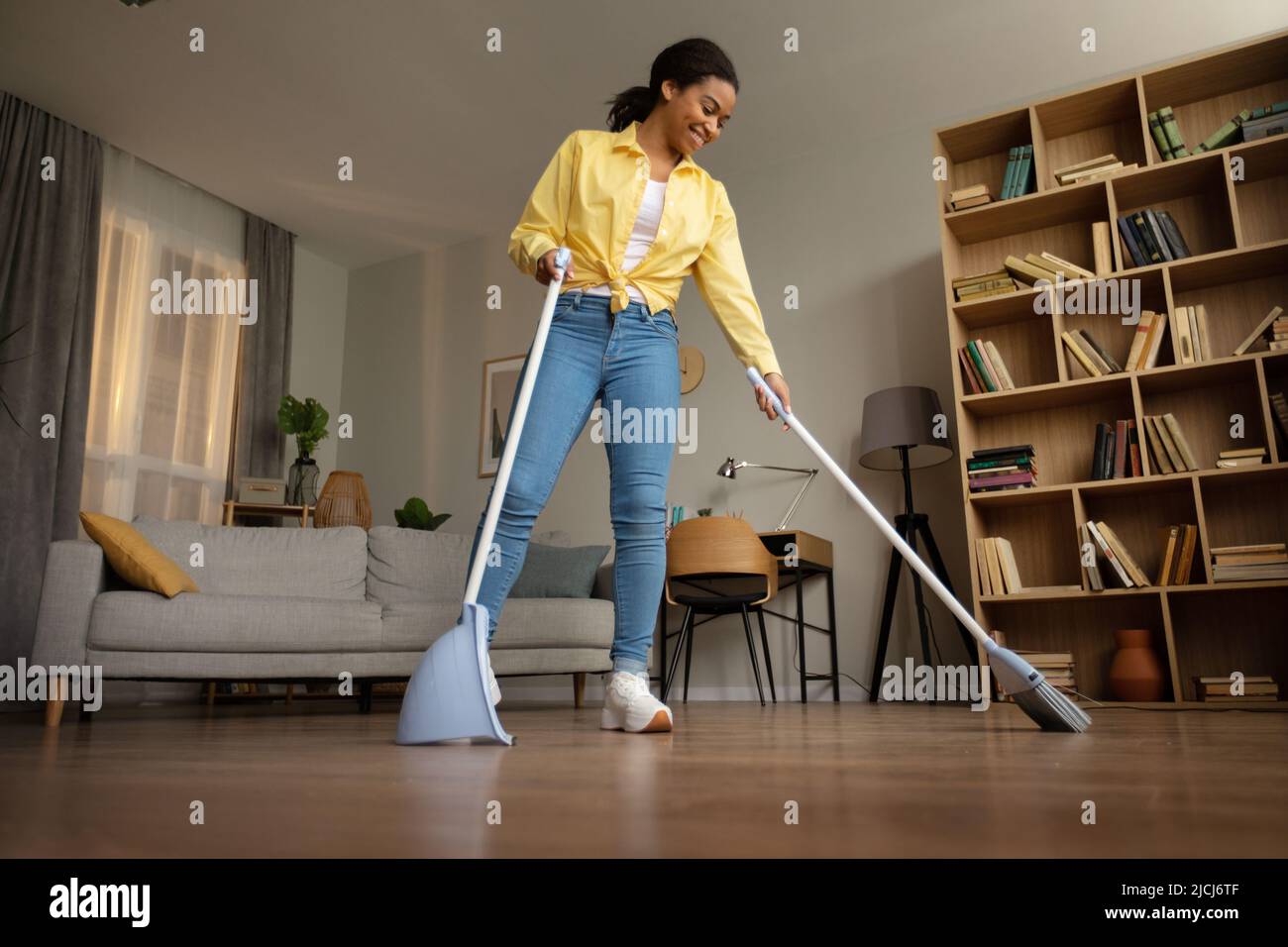 African Lady Sweeping Floor Using Broom And Scoop Cleaning Home Stock Photo