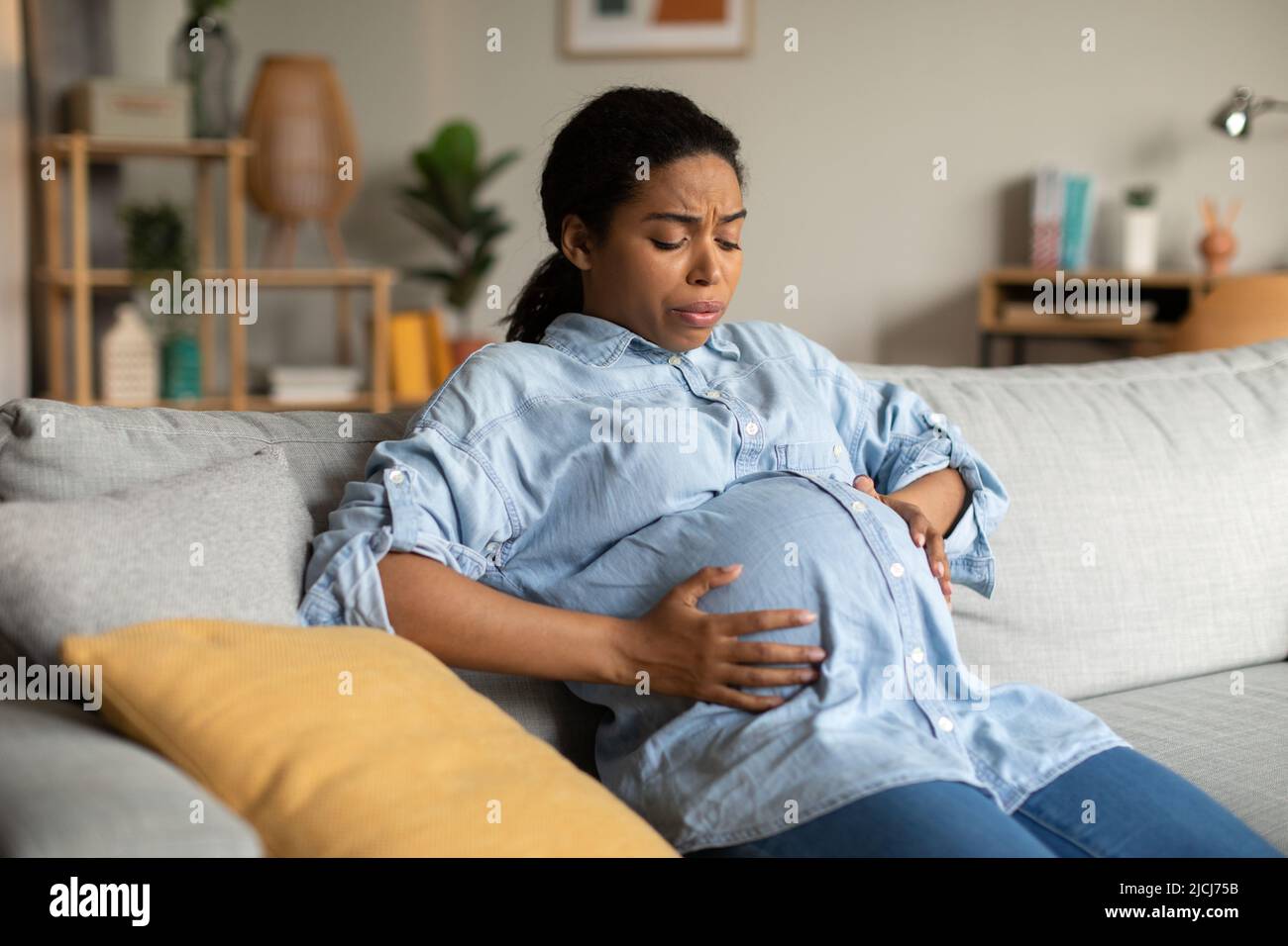 Pregnant African Woman Suffering From Pain Having Spasm At Home Stock Photo