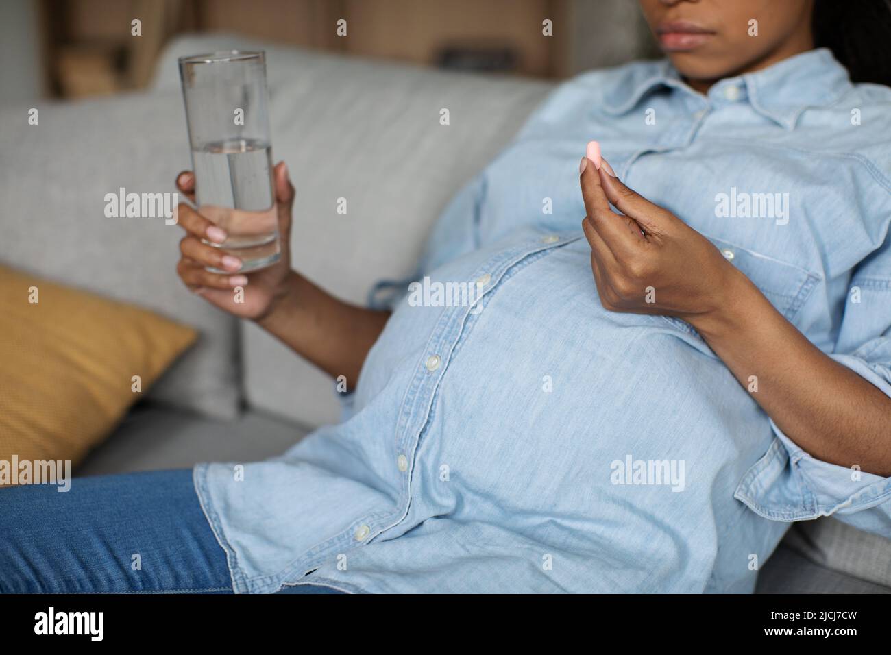 Unrecognizable Pregnant Black Woman Taking Pill Holding Glass At Home Stock Photo