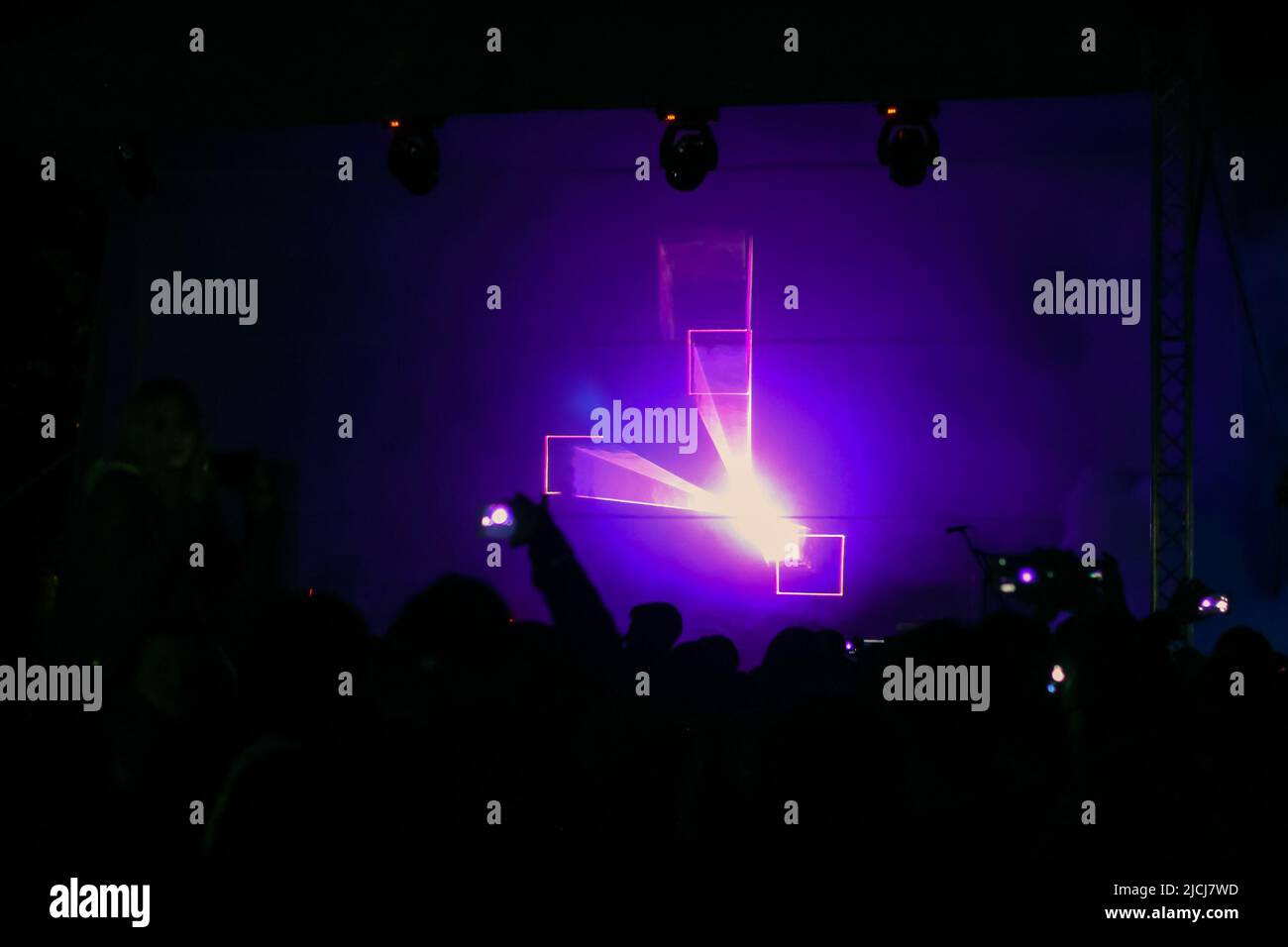 Purple laser neon beams. Crowd of people watching laser show at street festival. Many people enjoy the concert. Stock Photo