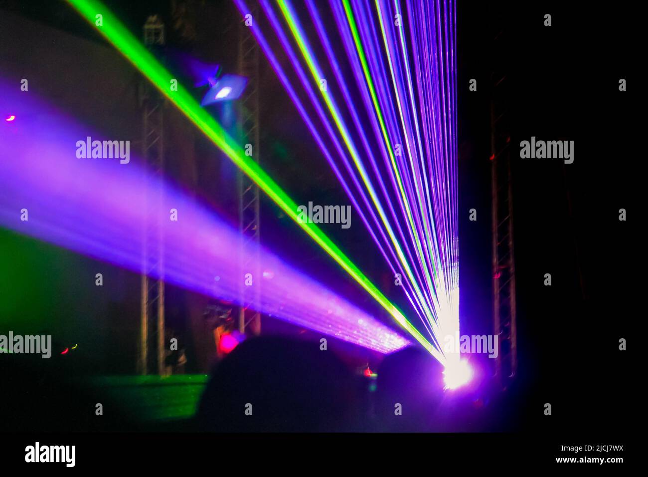 Purple laser neon beams. Crowd of people watching laser show at street festival. Many people enjoy the concert. Stock Photo