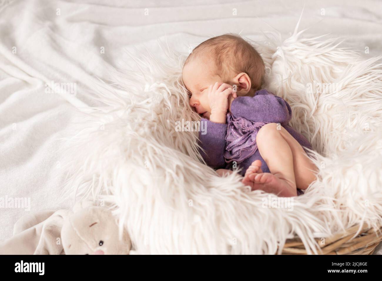 Cute newborn baby girl sleeping in a basket with a fluffy white blanket
