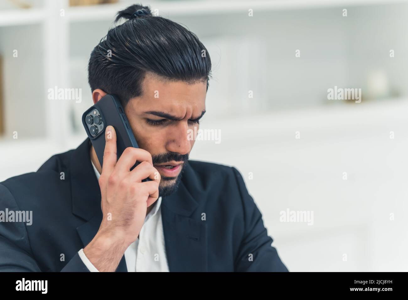 Annoyed combed handsome cuban man wearing a black suit and a white shirt talking on the phone, discussing business. High quality photo Stock Photo