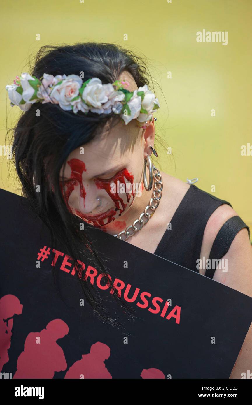 A young Ukrainian protester head bowed and face painted in Red holds a placard that reads, ‘#TERRORUSSIA', during a demonstration outside the Russian embassy in The Hague. Ukrainians refugees and supporters celebrated ‘Russia Day' outside the Russian embassy in The Hague. A national holiday in the Russian Federation and celebrated annually on the 12 June. This day was officially known as the ‘Day of Adoption of the Declaration of State Sovereignty of the Russian Federation'; and has the unofficial title of “Independence Day”. Today's protesters mockingly referred to it as President Putin's las Stock Photo