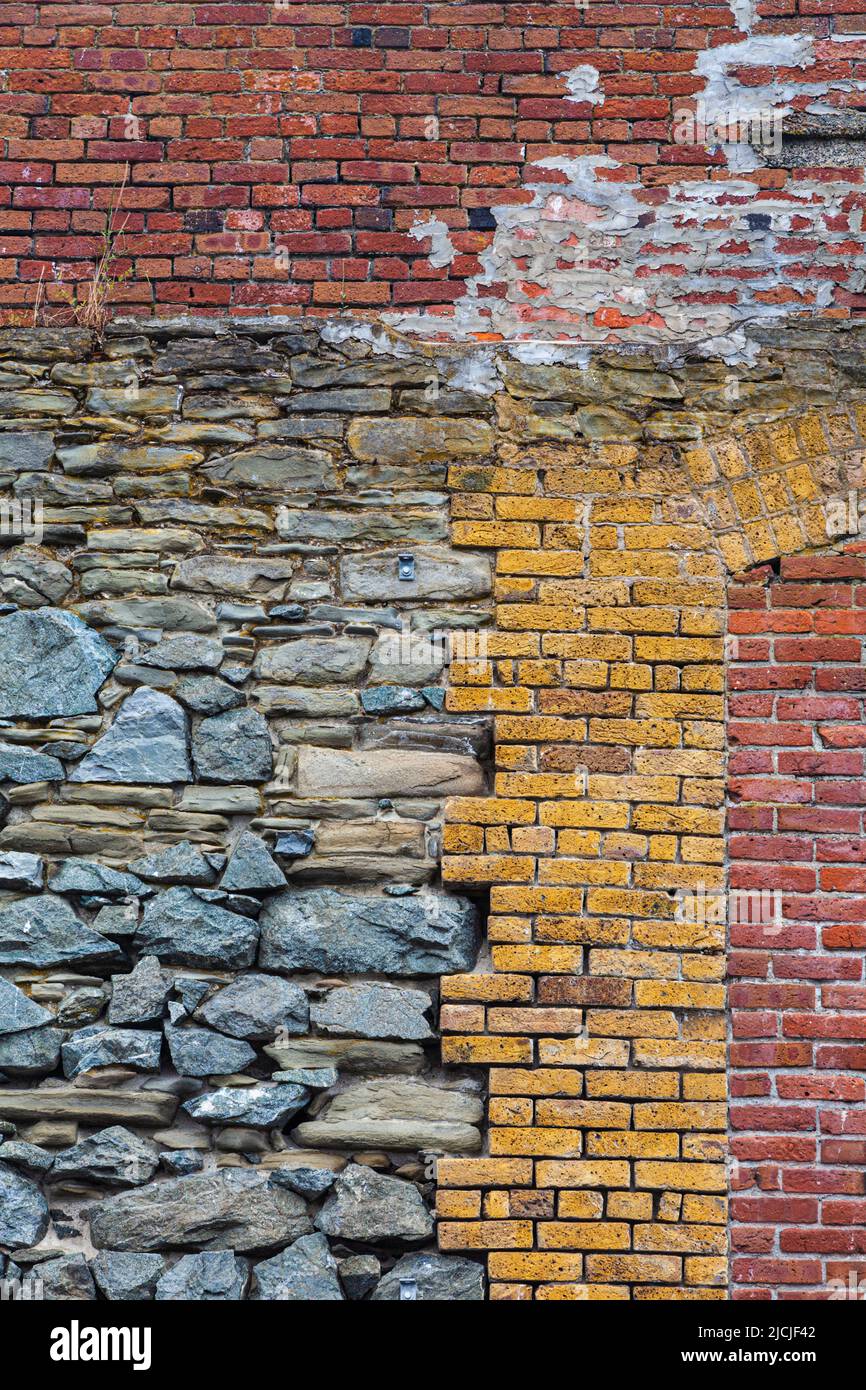 Abstract image of red and yellow brickwork amid rough stonework of a large retaining wall on the Victoria waterfront in British Columbia Canada Stock Photo