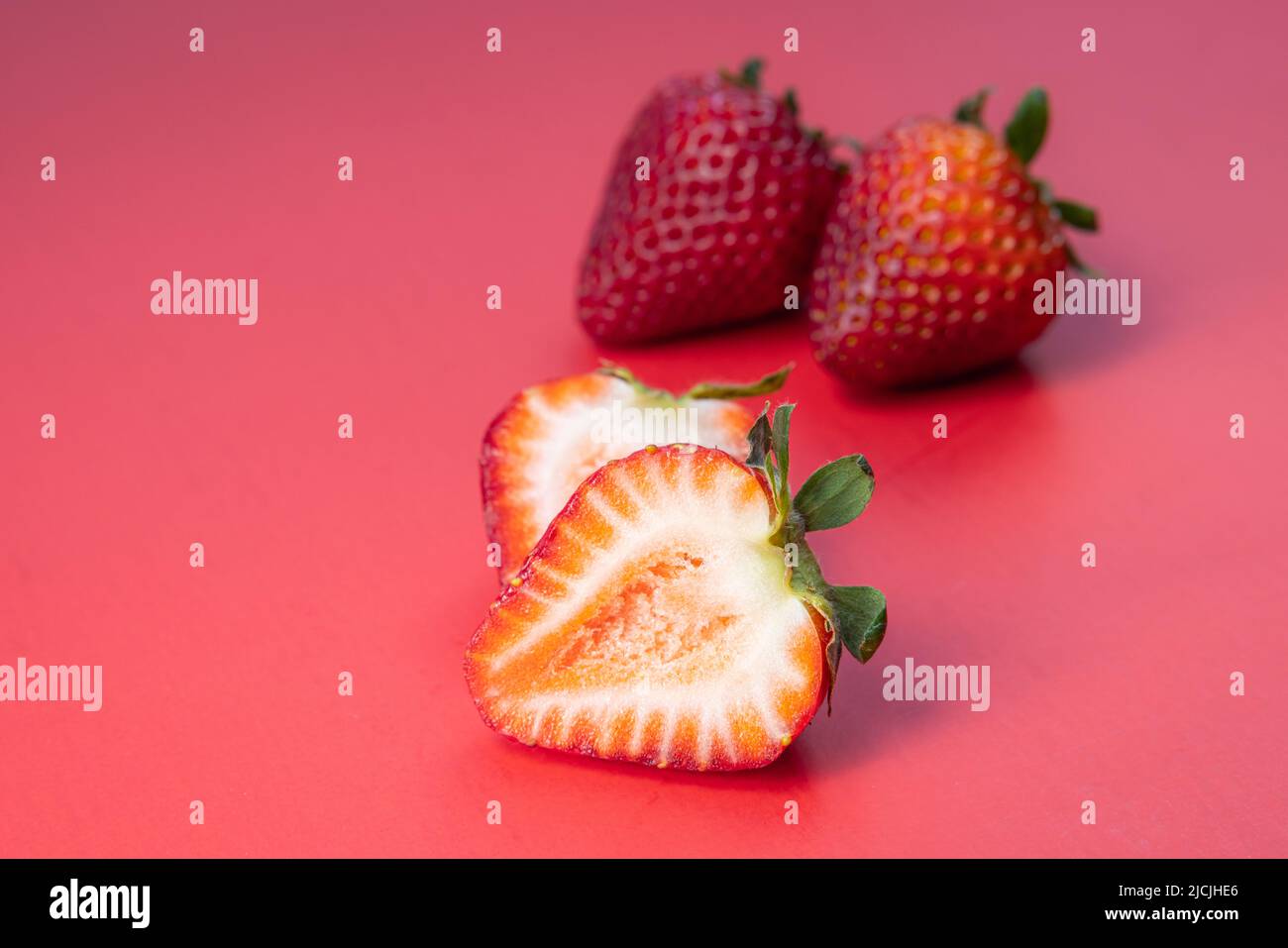 Fresh ripe juicy strwaberries isolated on a red background Stock Photo
