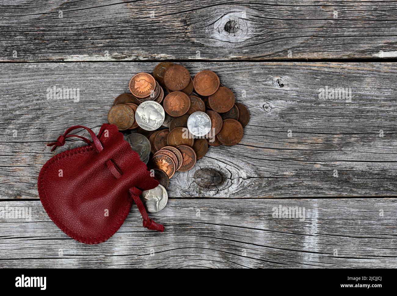 Small red leather bag of United States vintage coins on rustic wood background Stock Photo