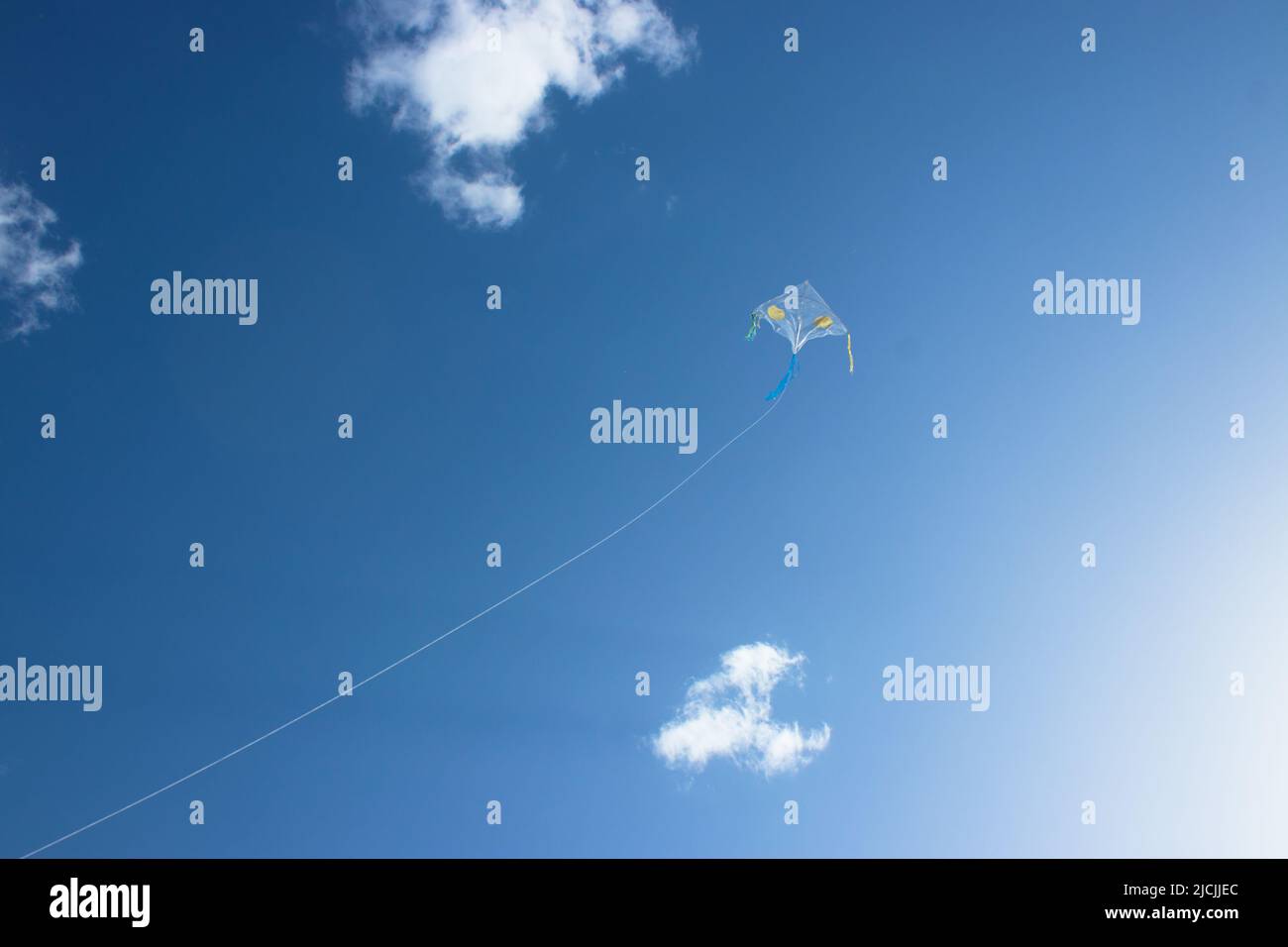 A kite floating in the sky. A blue-tailed rectangular kite. There are ...