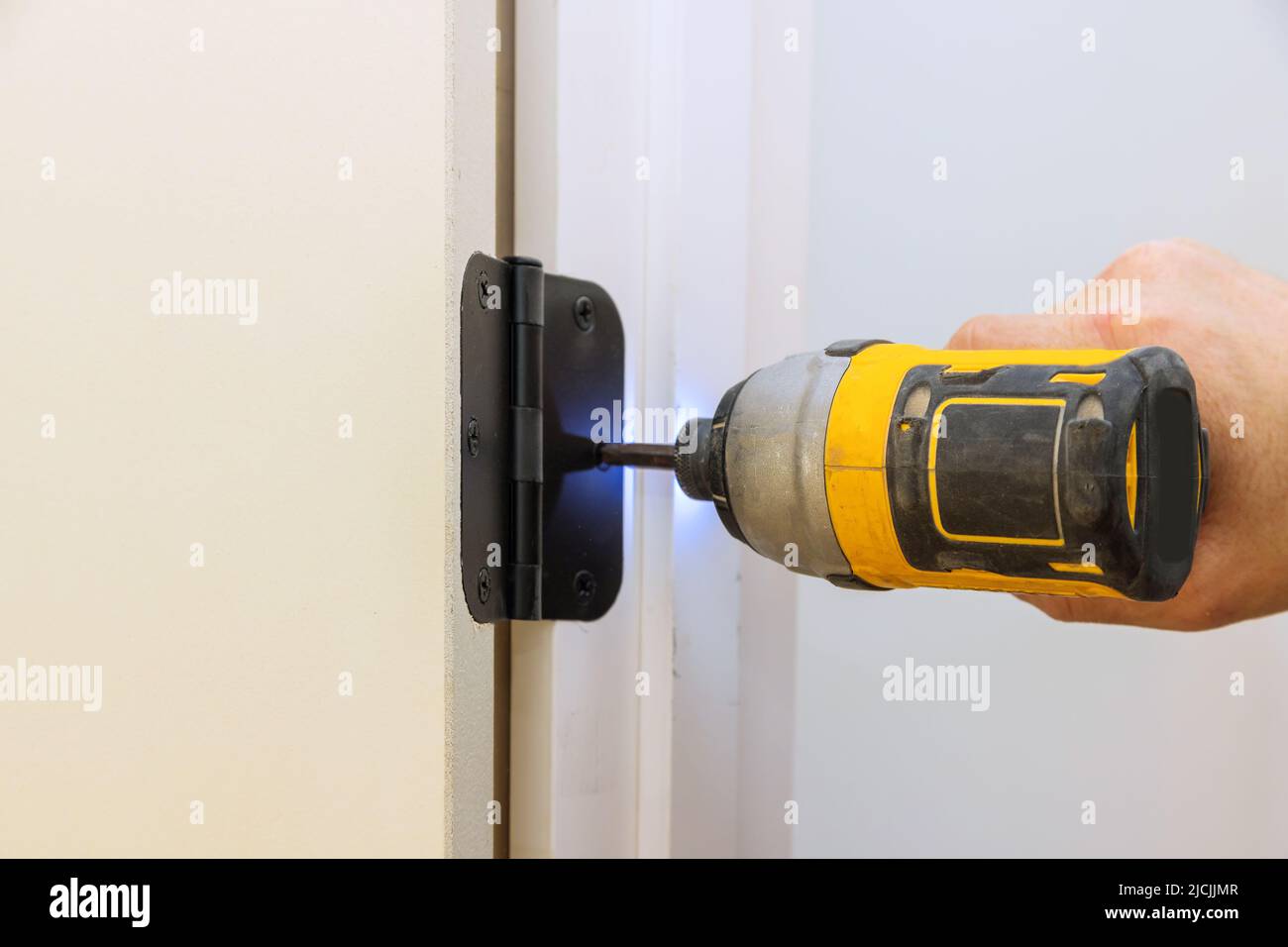 Installing the door hinge on the door frame using a screwdriver a home