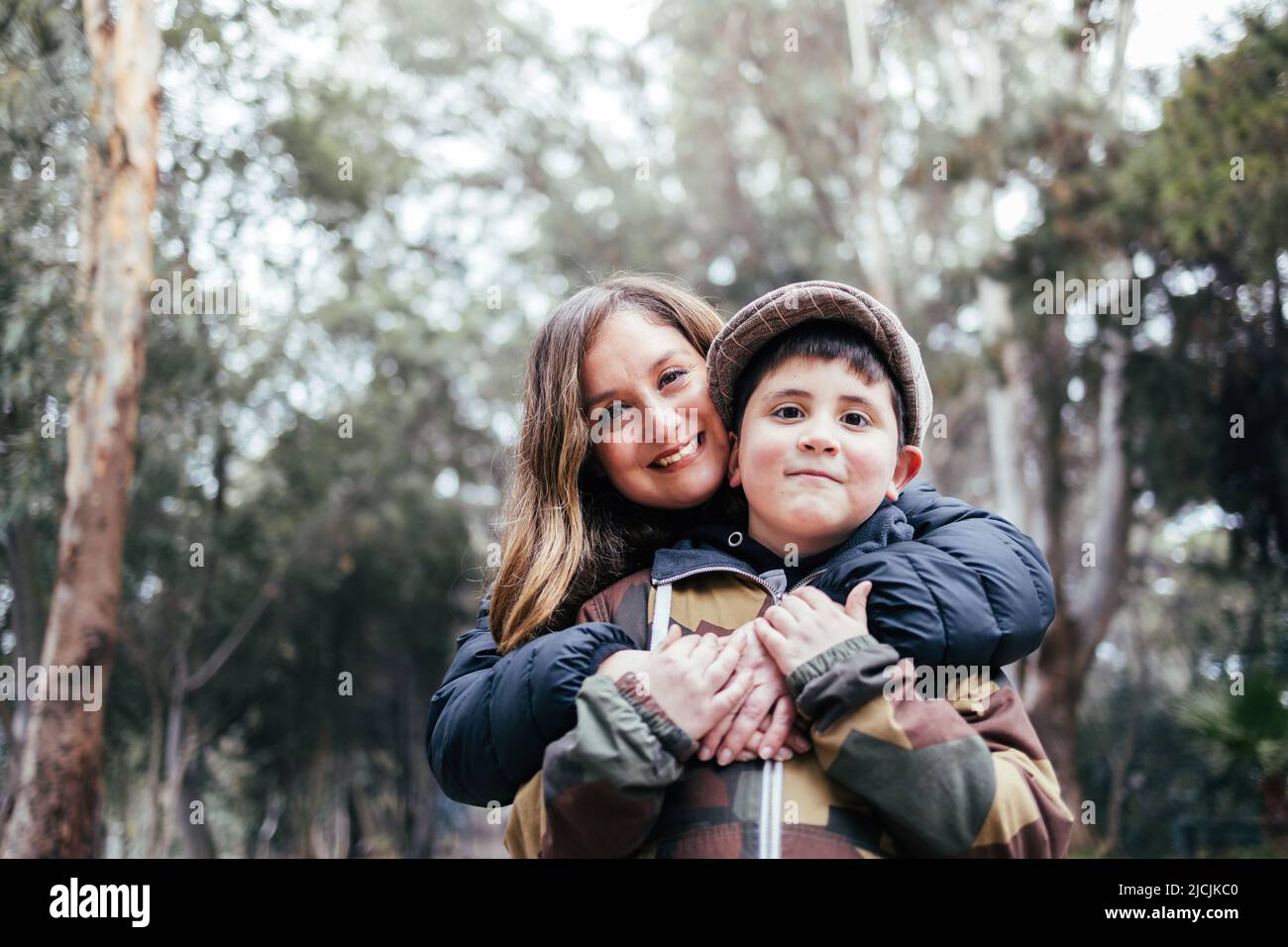 Single mother hugging her young son in the park. Single parent family Stock Photo
