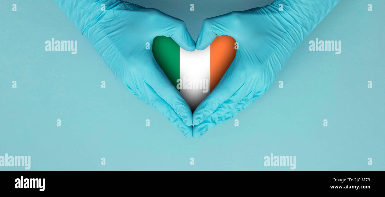Doctors hands wearing blue surgical gloves making hear shape symbol with ireland flag Stock Photo