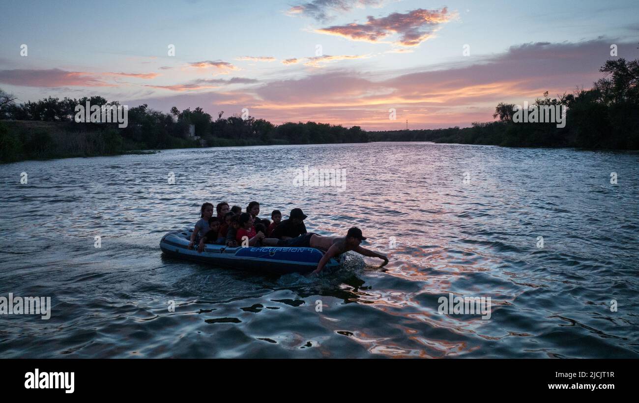A smuggler uses his hands to paddle on a raft full of asylum seeking migrants from Central and South America across the Rio Grande river into the United States from Mexico in Roma, Texas, U.S., June 13, 2022. Picture taken June 13, 2022. Picture taken with a drone.  REUTERS/Adrees Latif     TPX IMAGES OF THE DAY Stock Photo