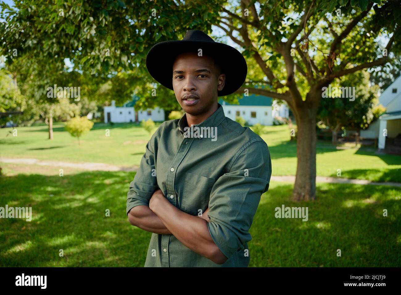 Mixed race farmer looking serious while standing outdoors with arms crossed Stock Photo