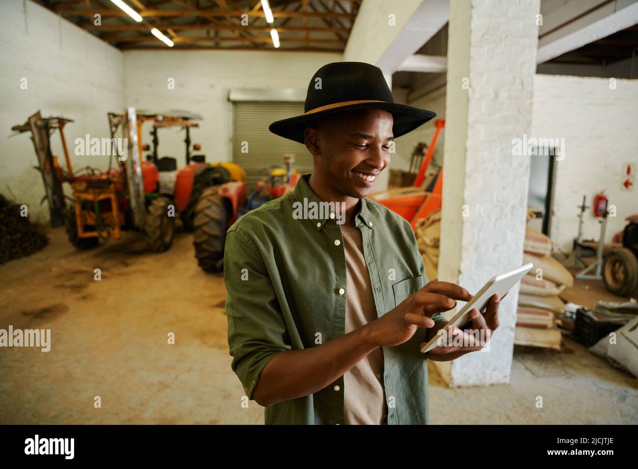 Mixed race male farmer standing in storeroom typing on digital tablet  Stock Photo