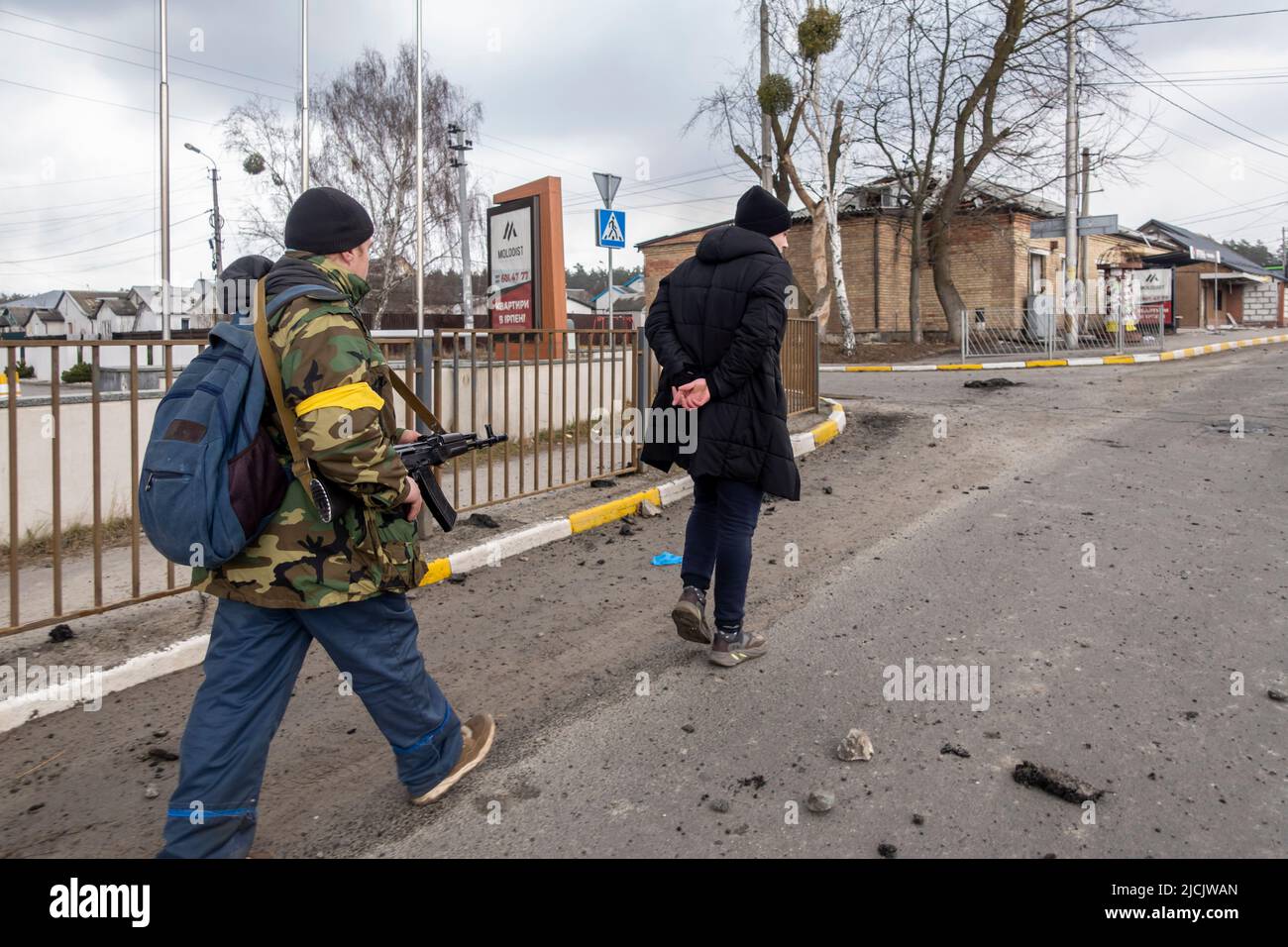 IRPIN, UKRAINE 03 March. A member of the Territorial defense forces aims his rifle as he walks behind a handcuffed man suspected  of helping Russian forces, as Russia's invasion of Ukraine continues on 03 March 2022 in Irpin, Ukraine. Russia began a military invasion of Ukraine on 24 February 2022 after Russia's parliament approved treaties with two breakaway regions in eastern Ukraine. It is the largest military conflict in Europe since World War II. Stock Photo