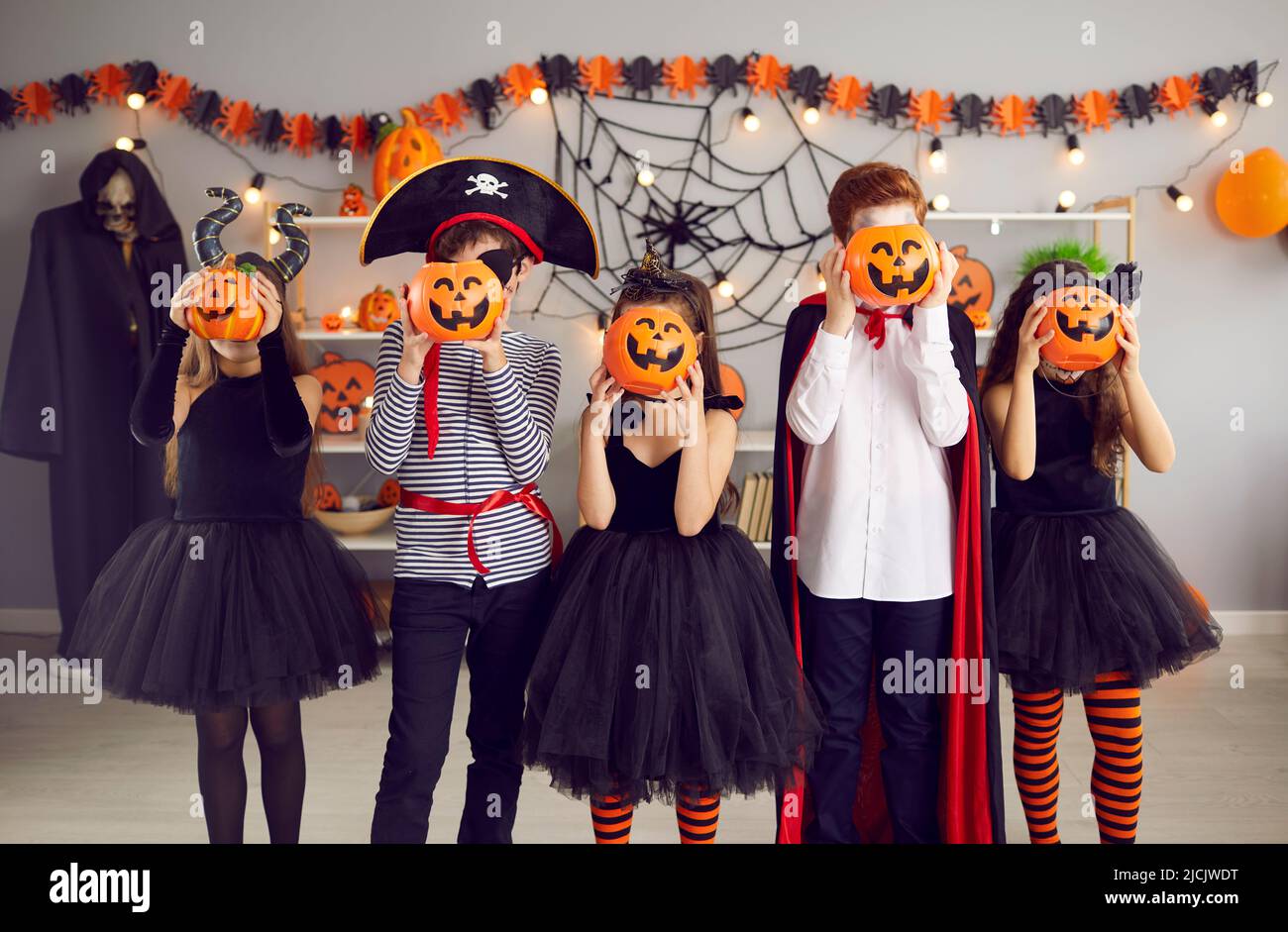 Children group in masquerade costumes pose with pumpkins Stock Photo