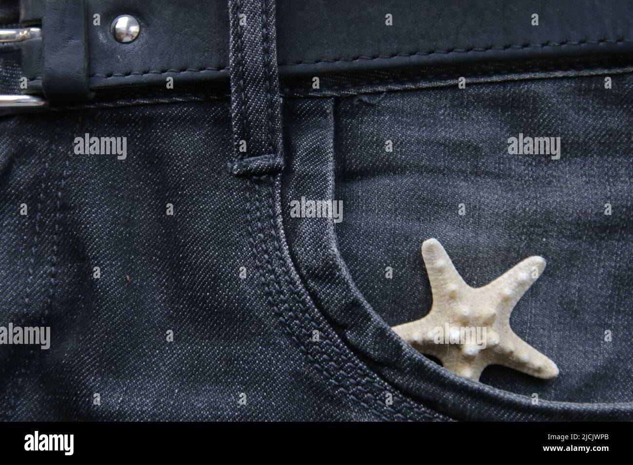 Vacation concept. A starfish in a jeans pocket. Stock Photo