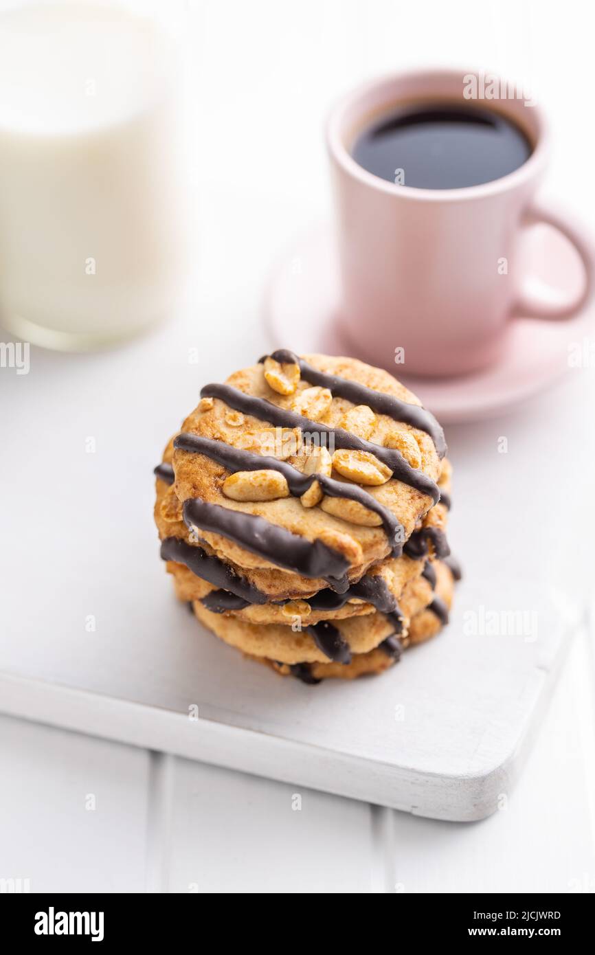 Chip cookies with peanuts and chocolate strips on a white table. Stock Photo