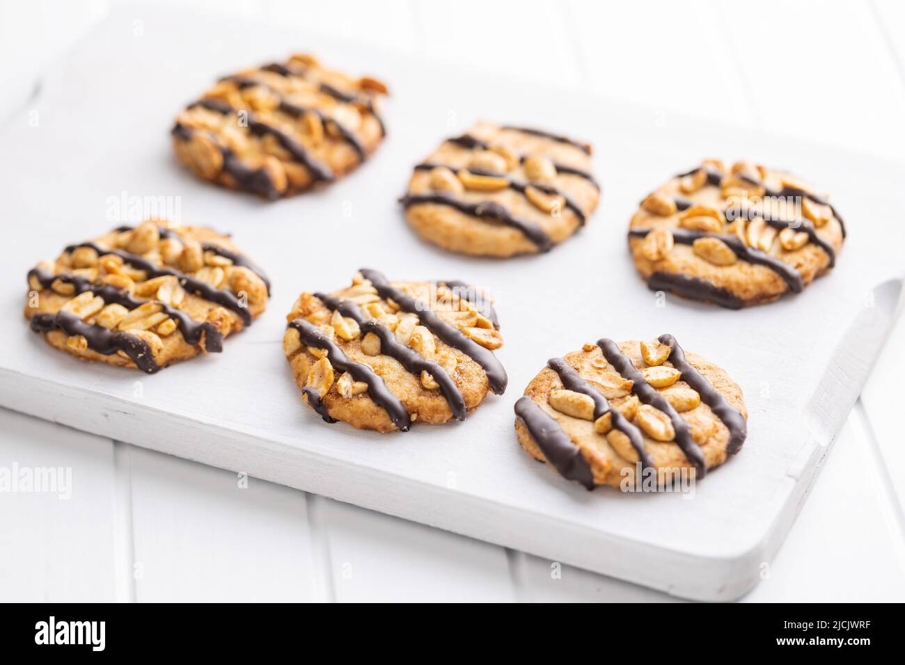 Chip cookies with peanuts and chocolate strips on a white table. Stock Photo
