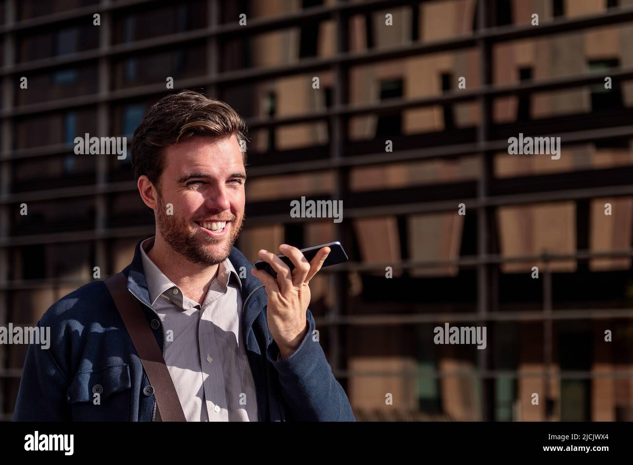 smiling young businessman sending a voice message Stock Photo