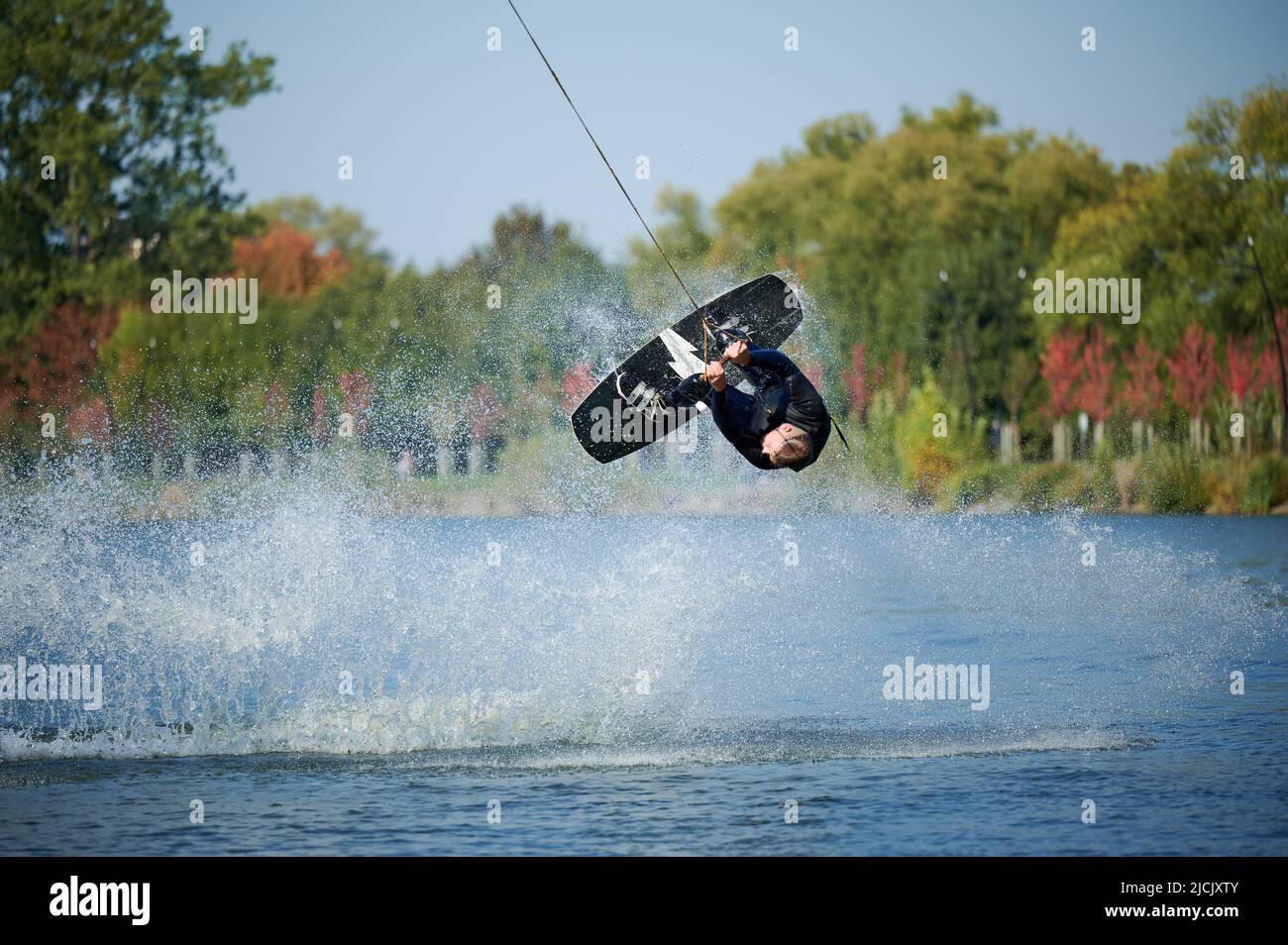 Wakeboarder making tricks while wakeboarding on lake. Young man surfer having fun wakesurfing in
