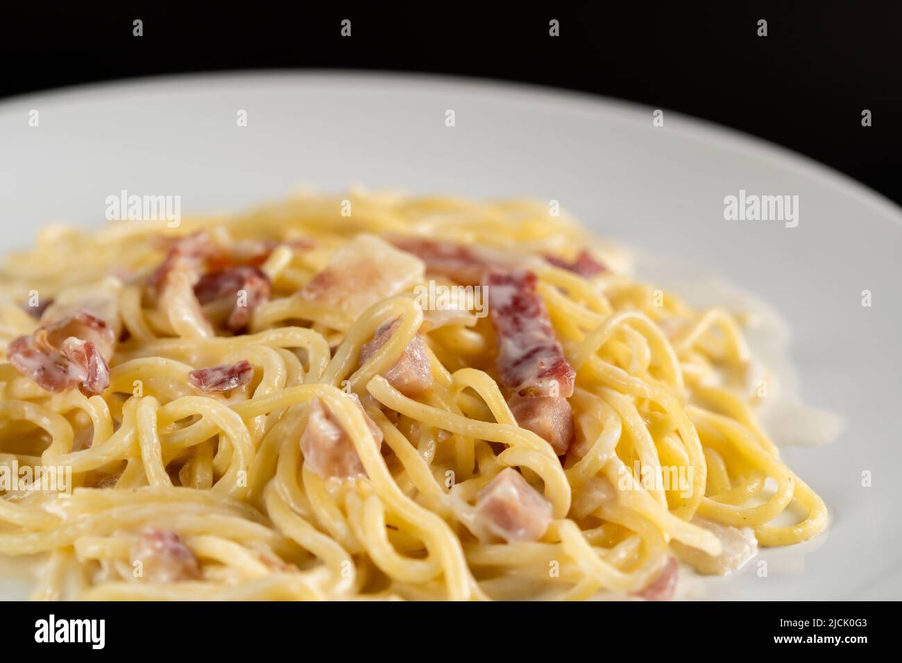 carbonara spaghetti with cream in white plate on a balck backgroud Stock Photo