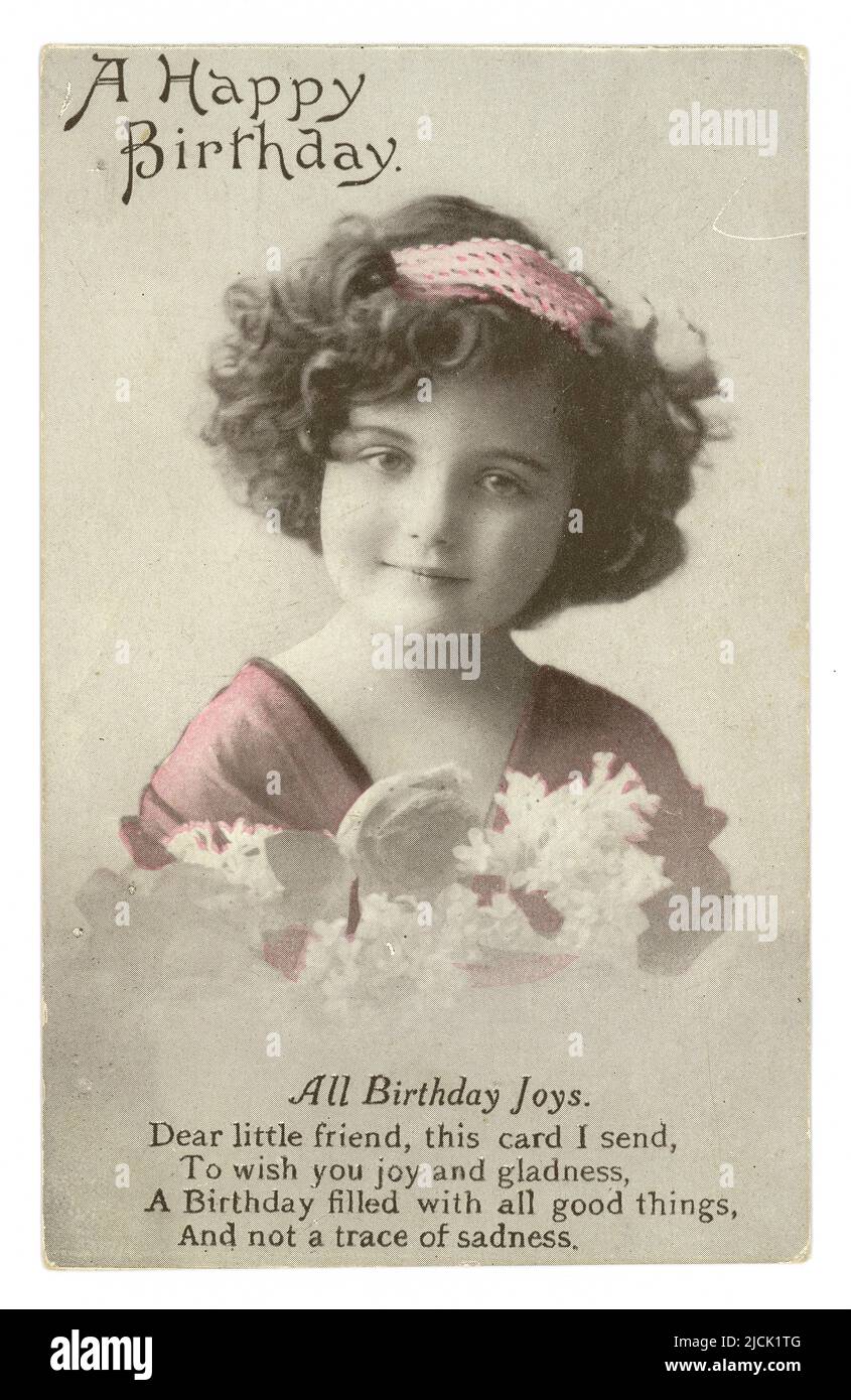 WW1 era sweet birthday greetings postcard wishing a friend a happy birthday. This tinted postcard is of a young girl, a regular model for these types of cards. She is wearing a headband and holding a bunch of flowers, poem on birthday joys, circa 1915, U.K. Stock Photo