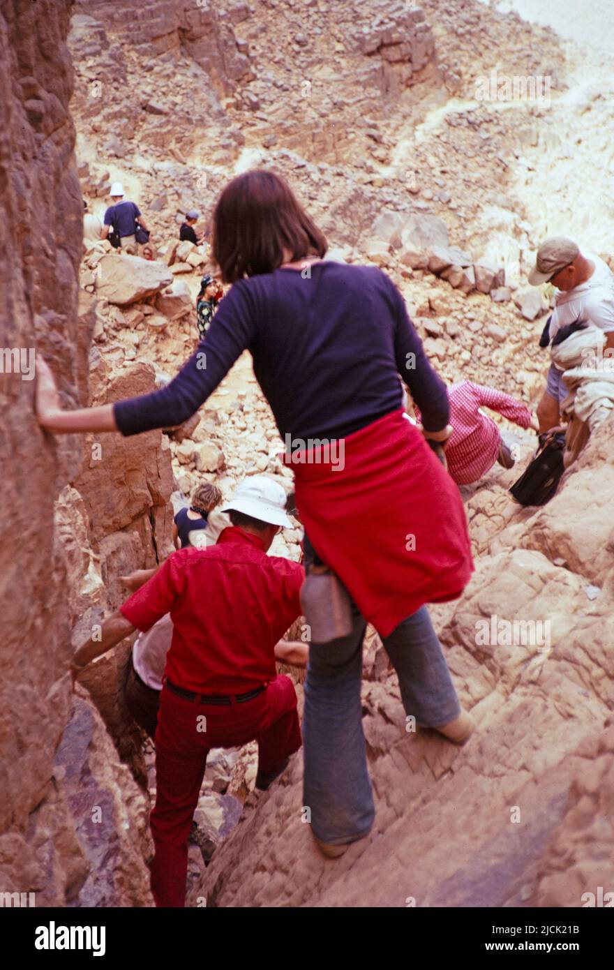 Tourists clambering down rocks visiting prehistoric sites, Tassili N'Ajjer National Park, Algeria, north Africa 1973 Stock Photo