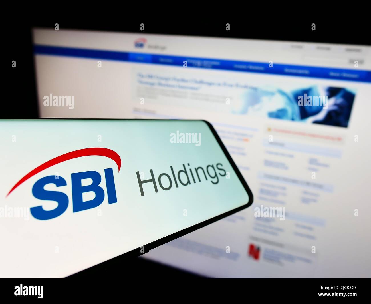 Smartphone with logo of Japanese financial company SBI Holdings on screen in front of business website. Focus on center of phone display. Stock Photo