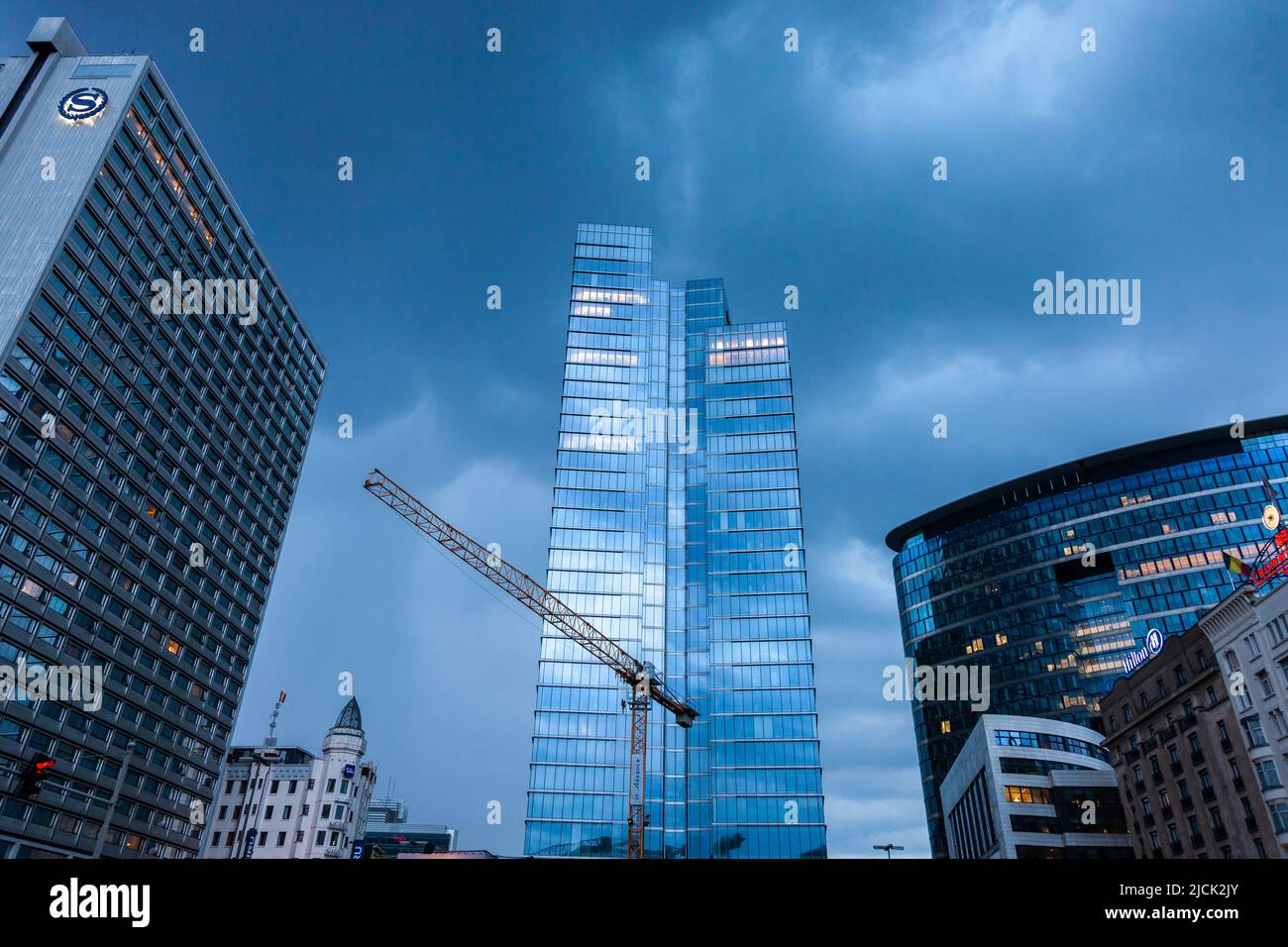 Skyscrapers with crane surrounding Place Rogier in Brussels on a stormy evening. Stock Photo