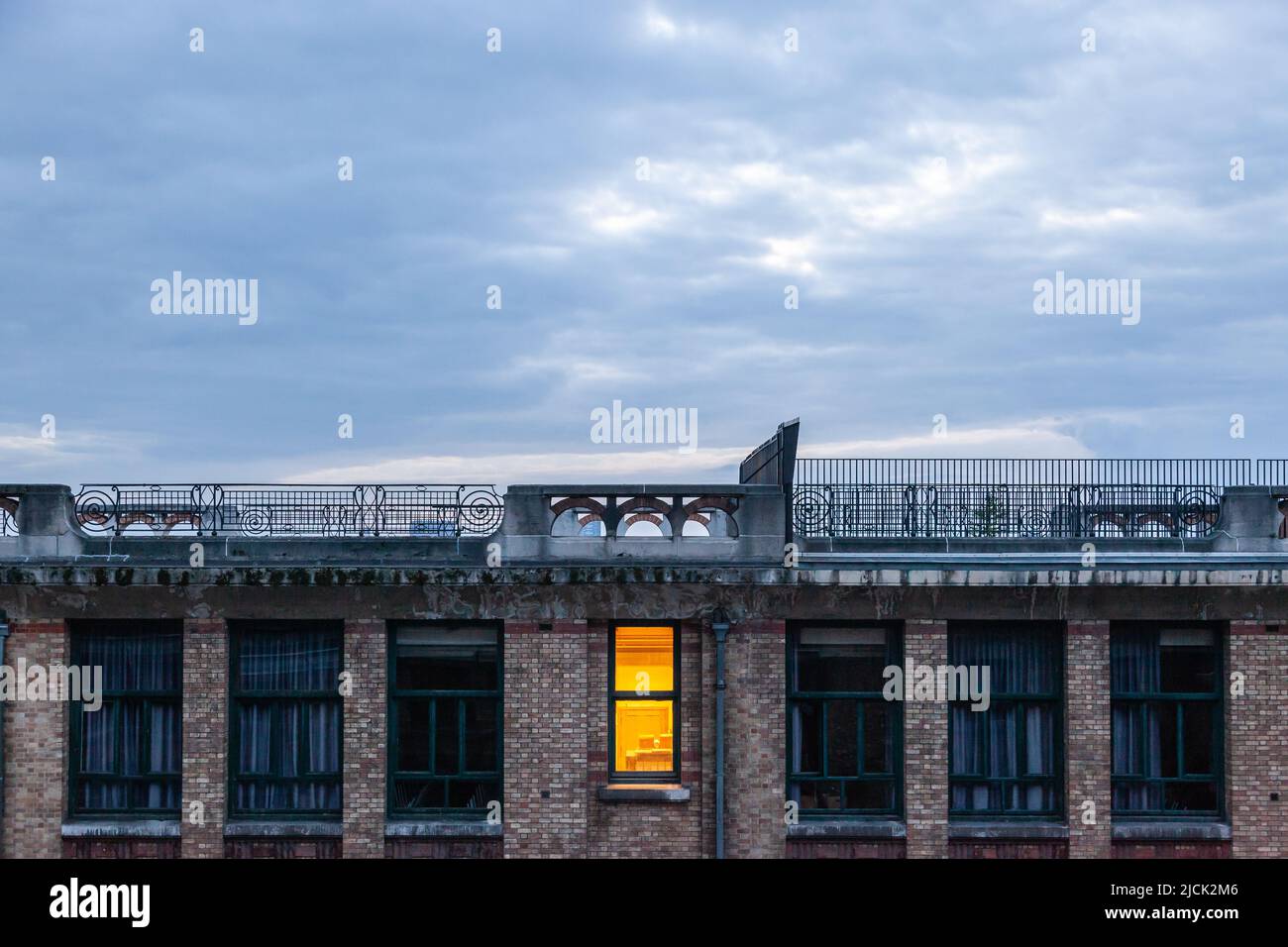 Single lit window of a dark building at dusk. Brussels. Stock Photo