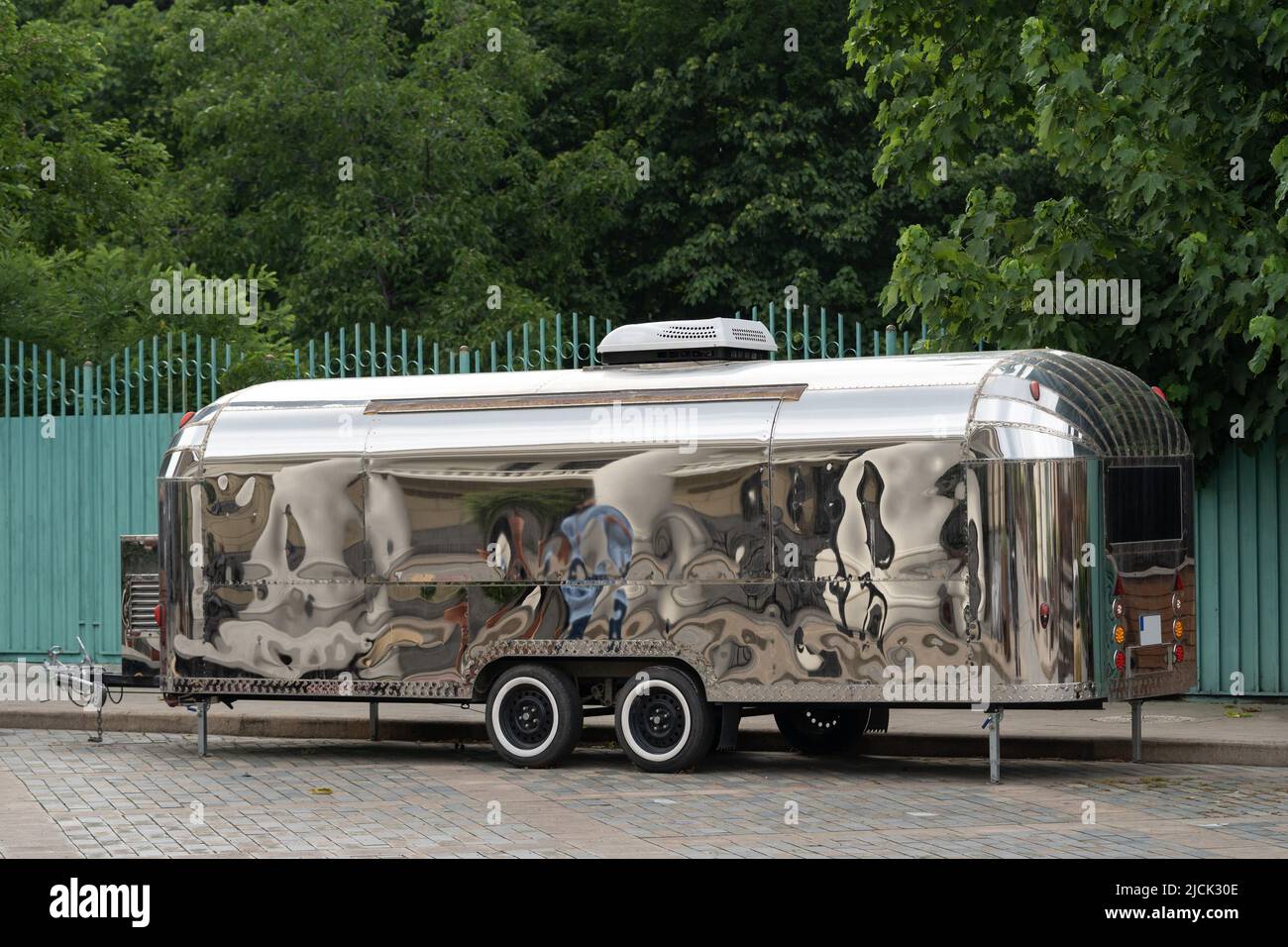Retro style futuristic silver metal trailer van standing on summer day for fair, festival or event. Stock Photo