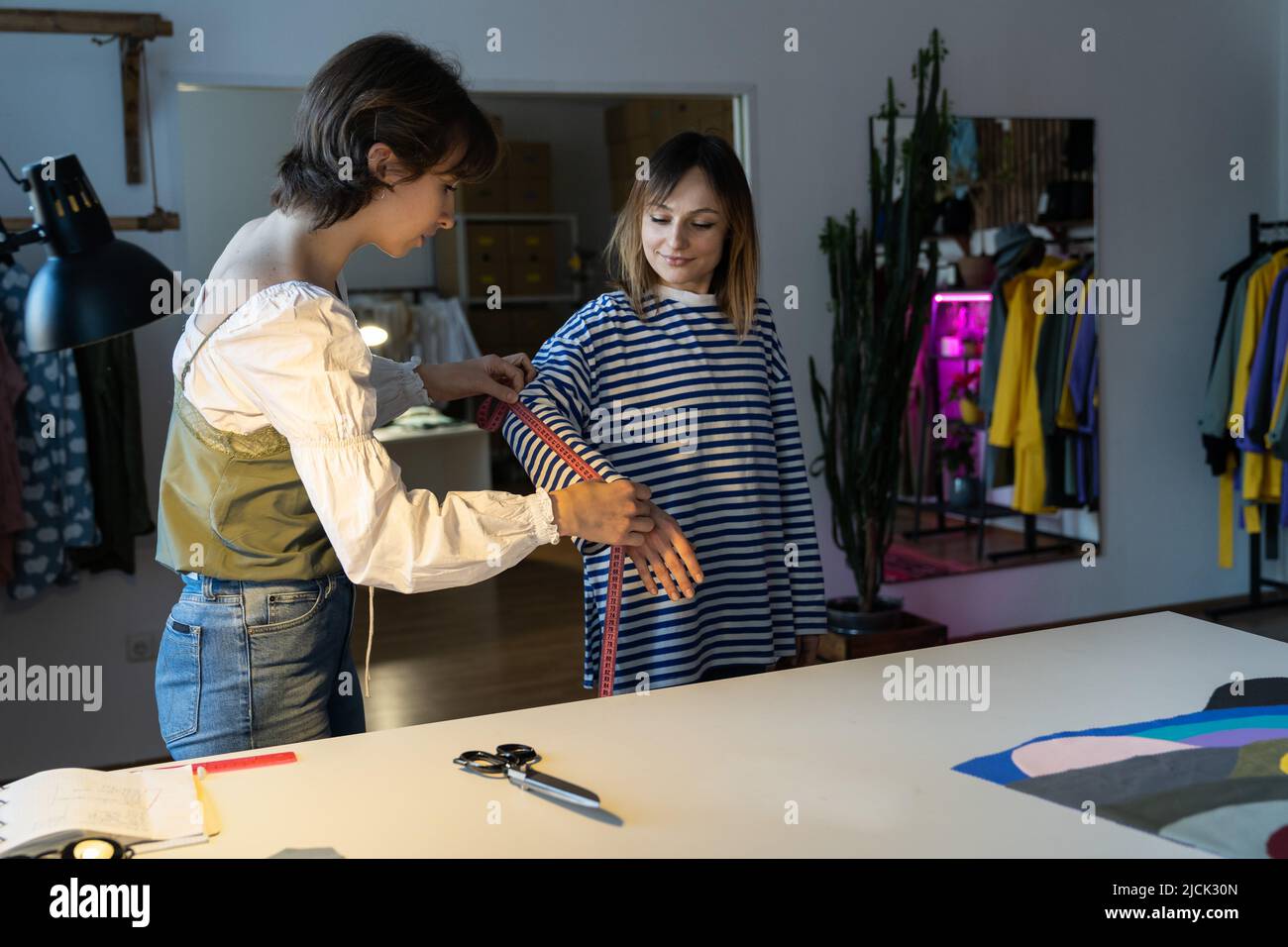 Fashion designer woman takes measurements with measuring tape of client ...