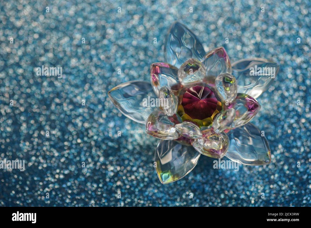 Crystal lotus on blue shiny sequins table. Vishuddha chakra symbol. Reiki meditation. Stock Photo