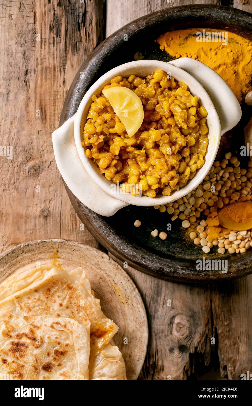 Dhal with roti bread. Traditional indian yellow pea food dal with roti flatbread, served with lemon in ceramic bowl on old wooden table. Flat lay, cop Stock Photo