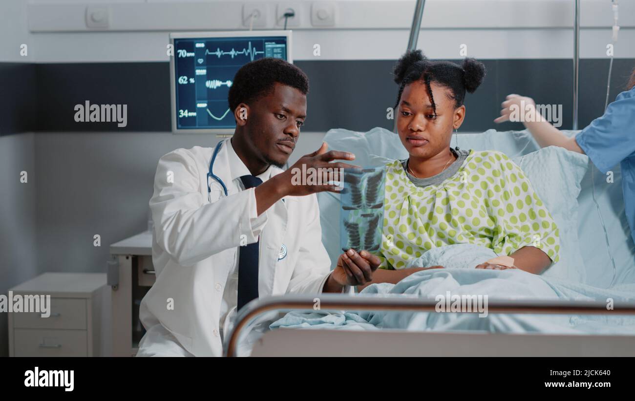 Man working as doctor analyzing x ray scan with sick patient in ...