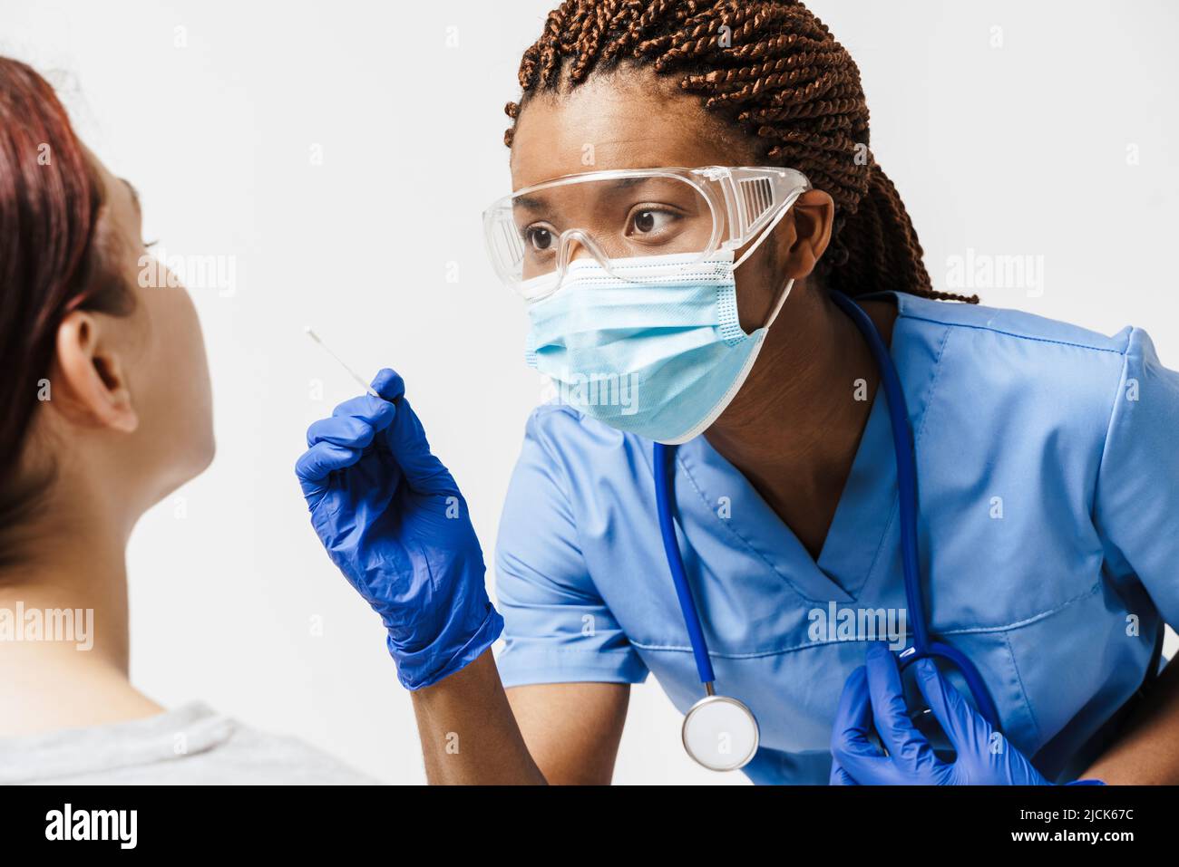 Black doctor wearing face mask making covid test to white woman ...